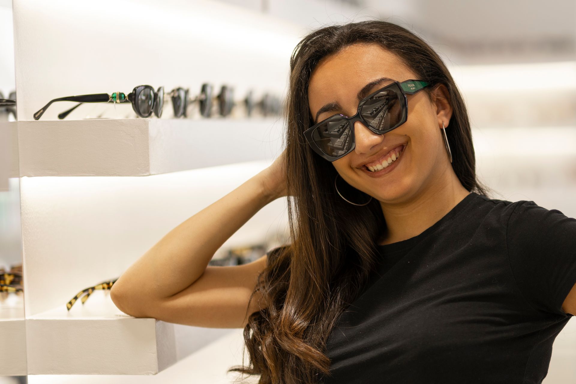 Una donna che indossa occhiali da sole e una maglietta nera sorride.