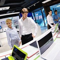 Two people looking at laptops in a brightly lit electronics store.