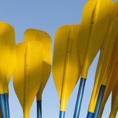 Yellow paddles with blue handles against a blue sky.