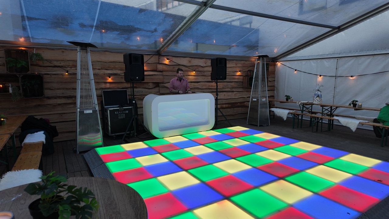 LED-dansvloer en DJ-booth in een frametent met transparant dak