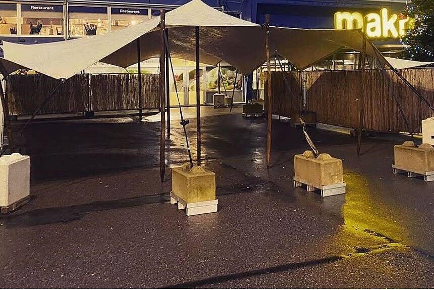 Ballastblokken op pallets bij een stretchtent op bestrating