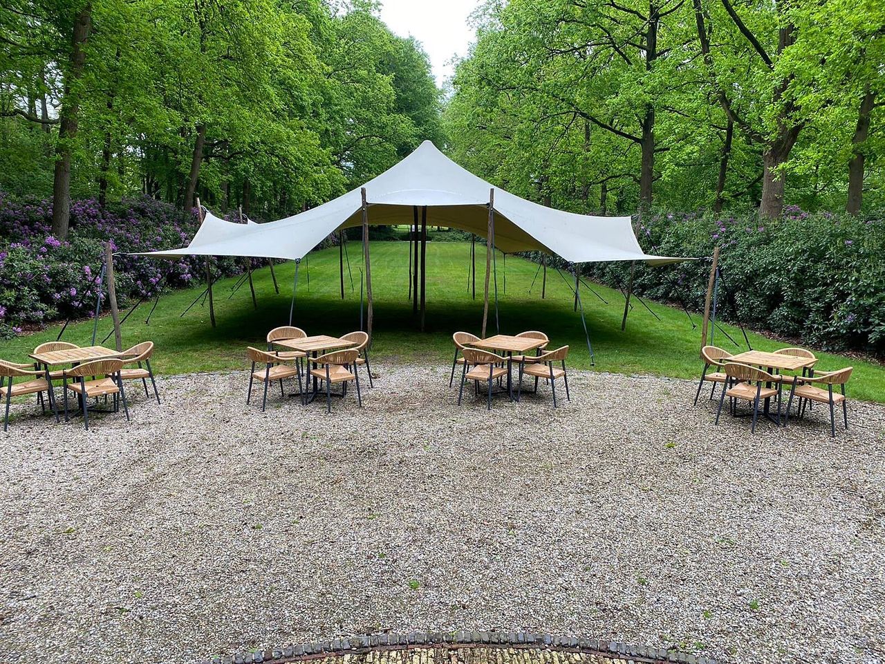 Stretchtent op een grindterrein met terrasstoelen