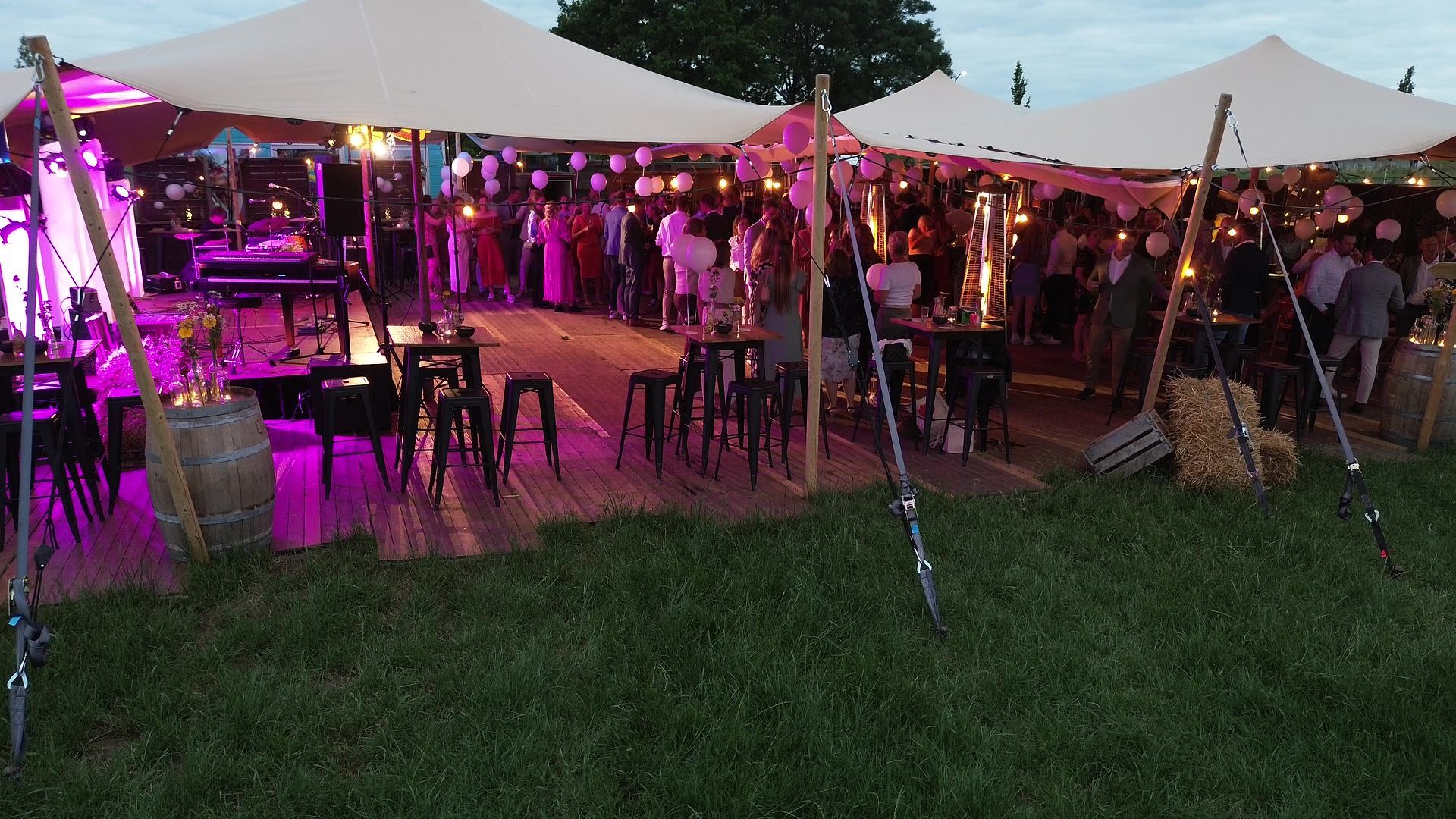 Stretchtenten met sfeerverlichting in de avond op een weiland