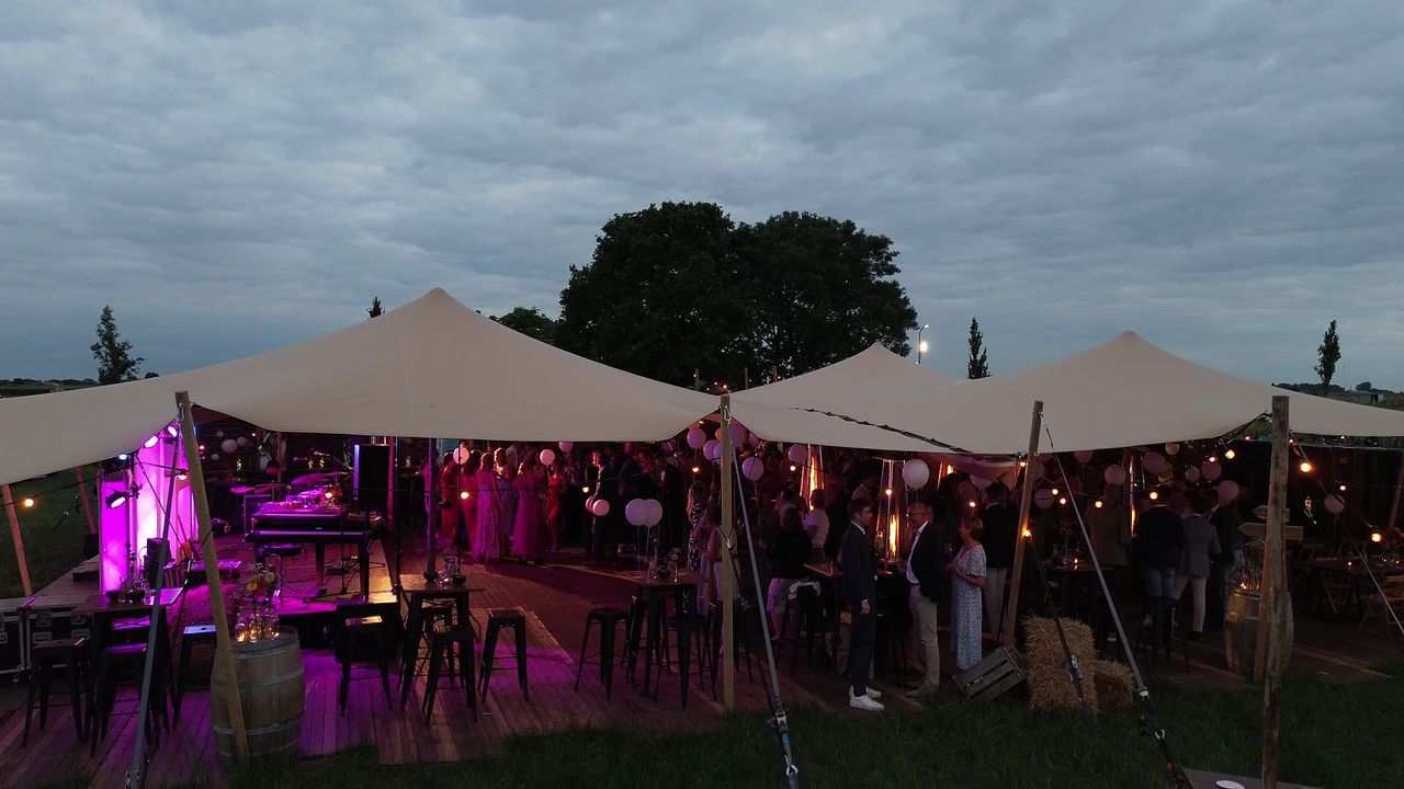 Stretchtent met verlichting en statafels in de schemering