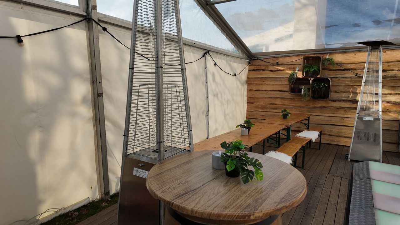 Lounge met ronde tafel en heater in de frametent