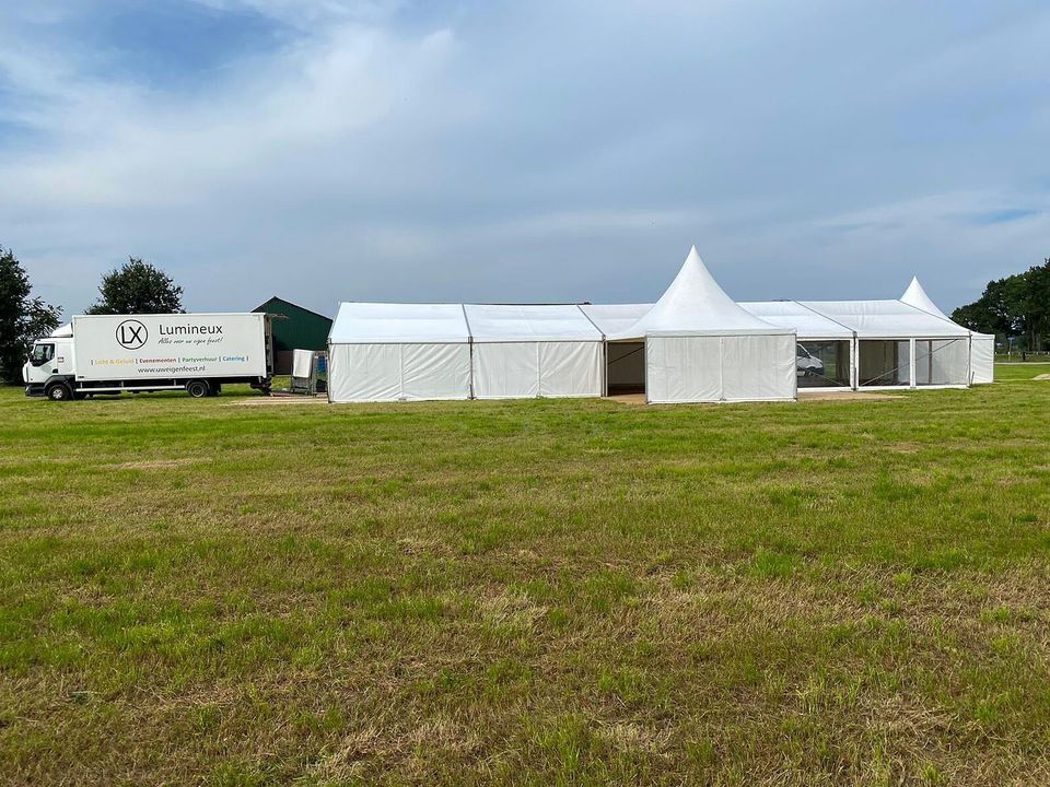 Witte frametent met pagode-ingang op een veld, van de zijkant