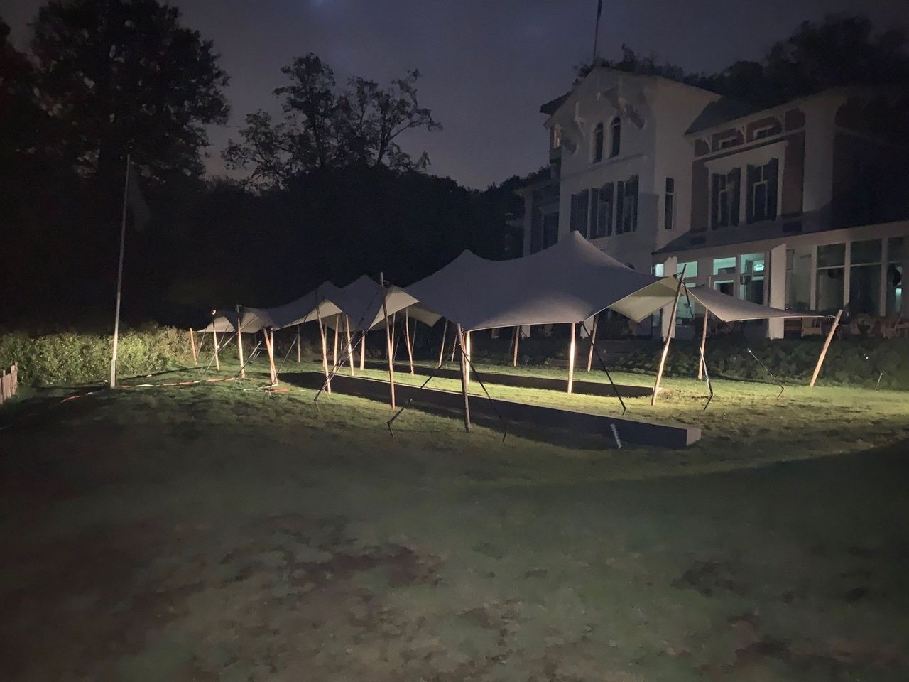 Stretchtent van 10 × 22 meter in de avond bij een landhuis