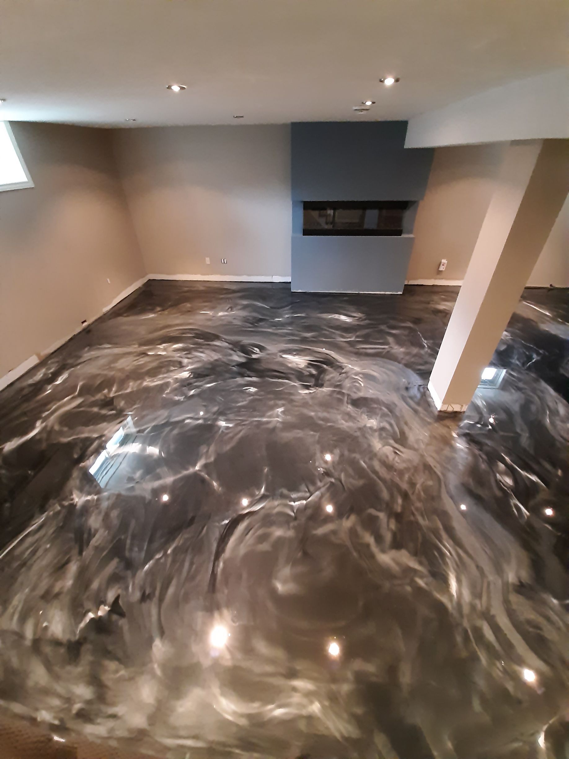 A basement with a metallic floor and a fireplace.