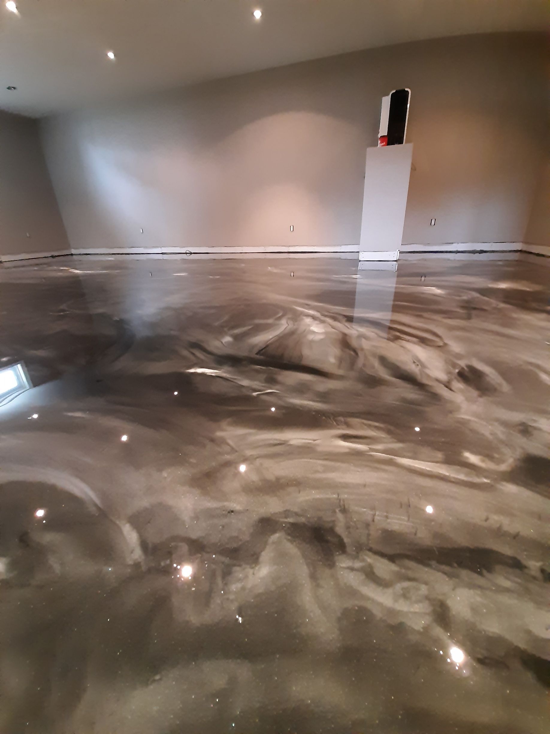 A shiny metallic floor in a basement with a reflection of lights.