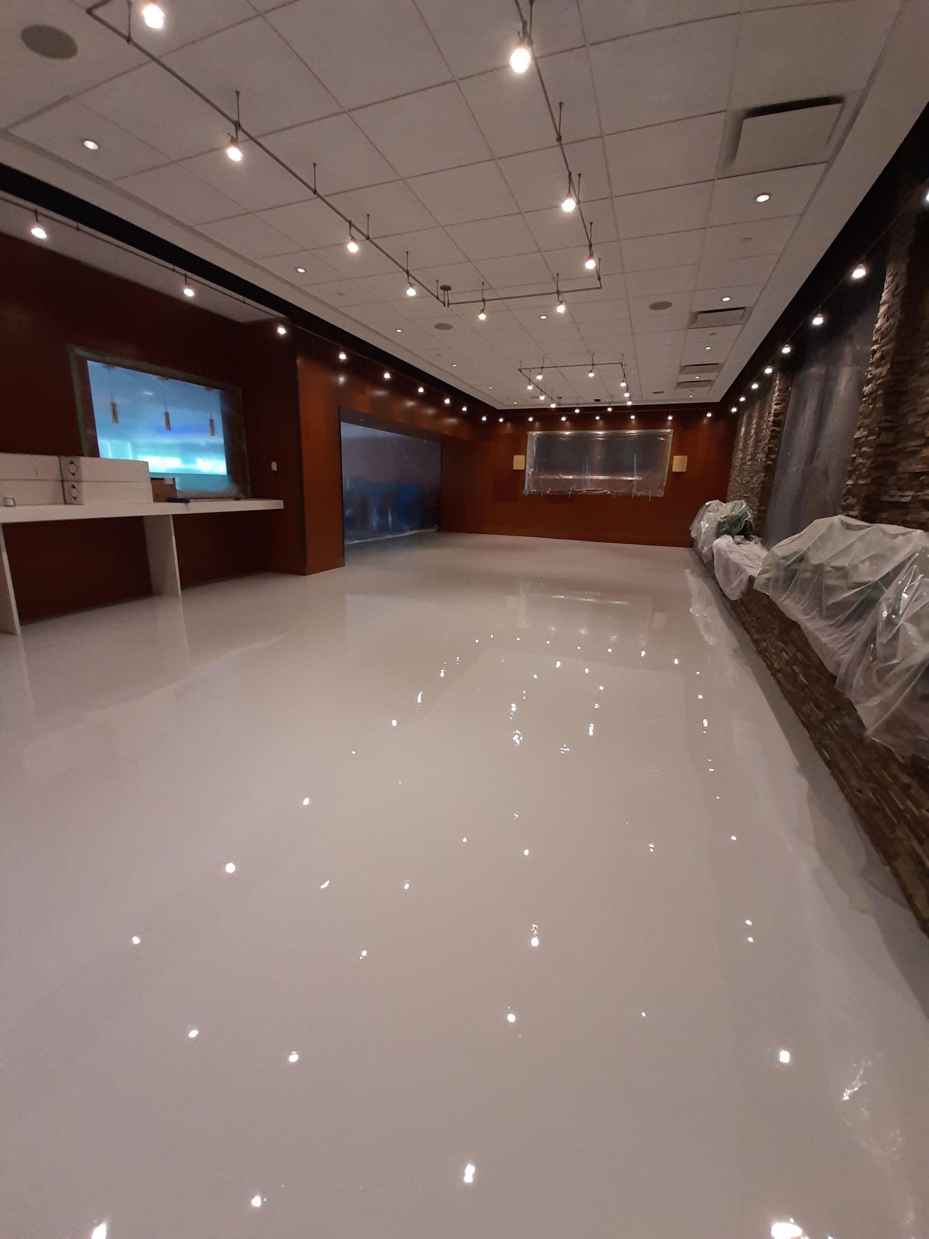 A large room with a white floor and a wooden wall.