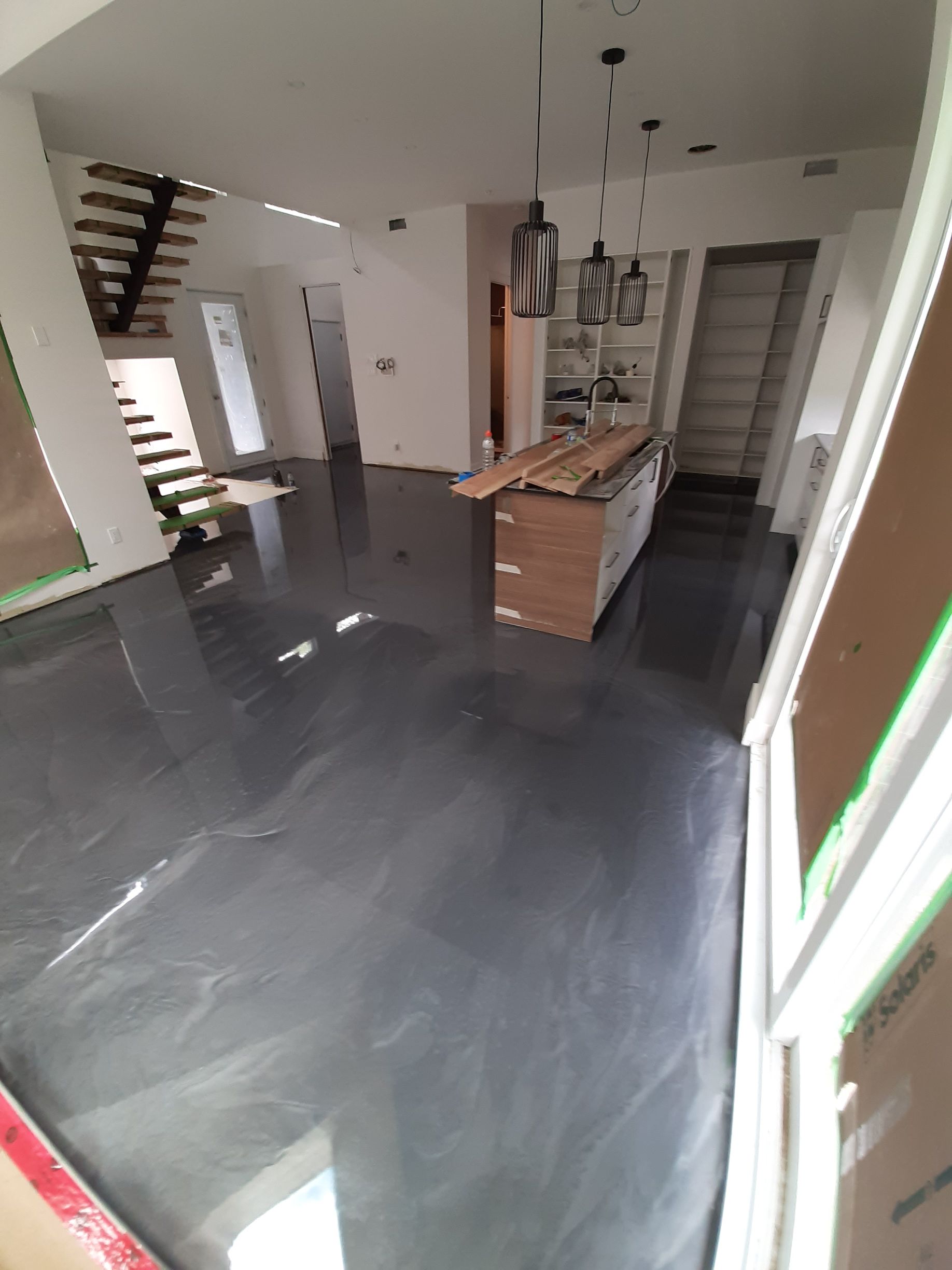 A room with a black floor and a staircase in the background.