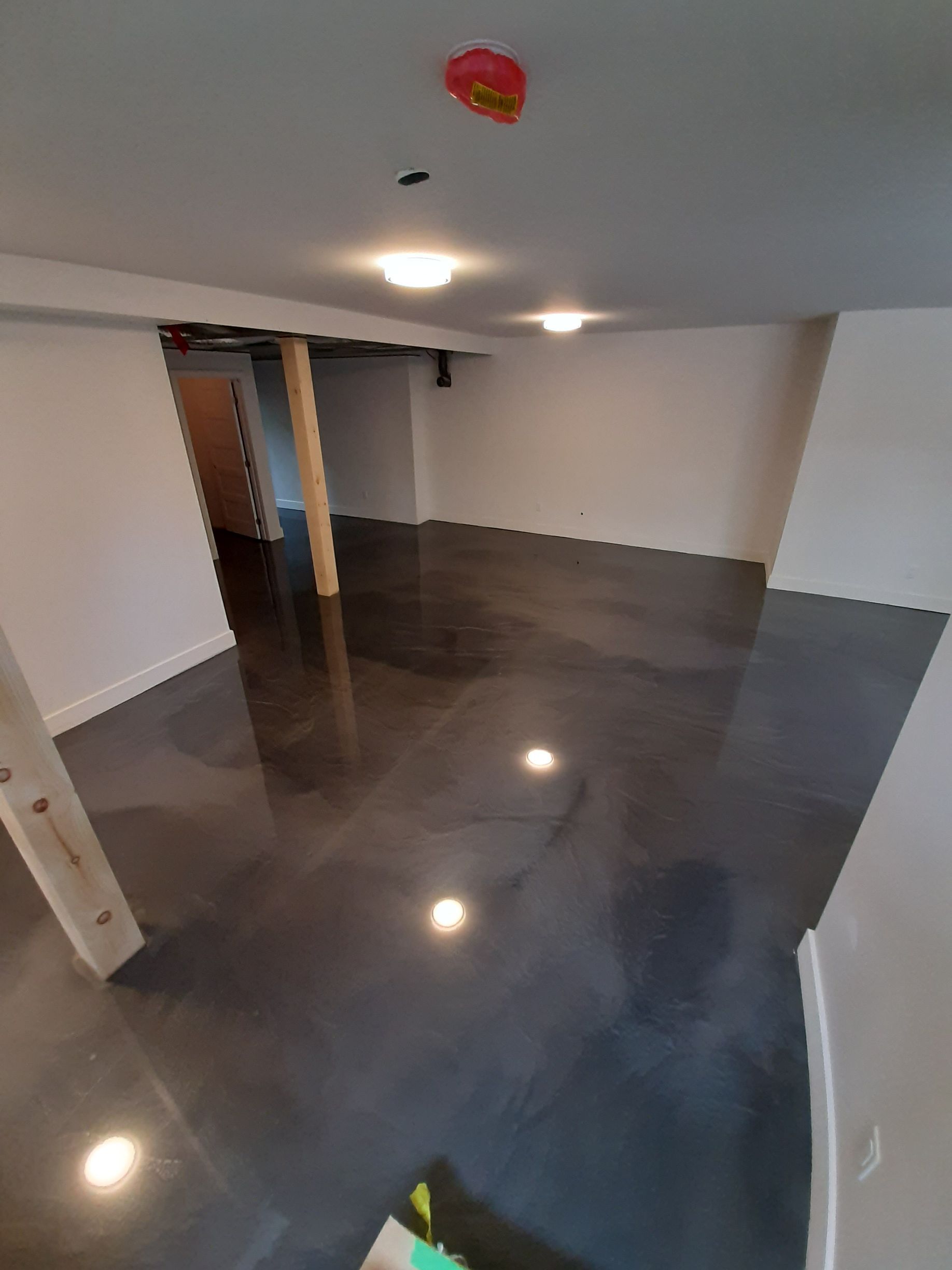 A basement with a shiny concrete floor and white walls.