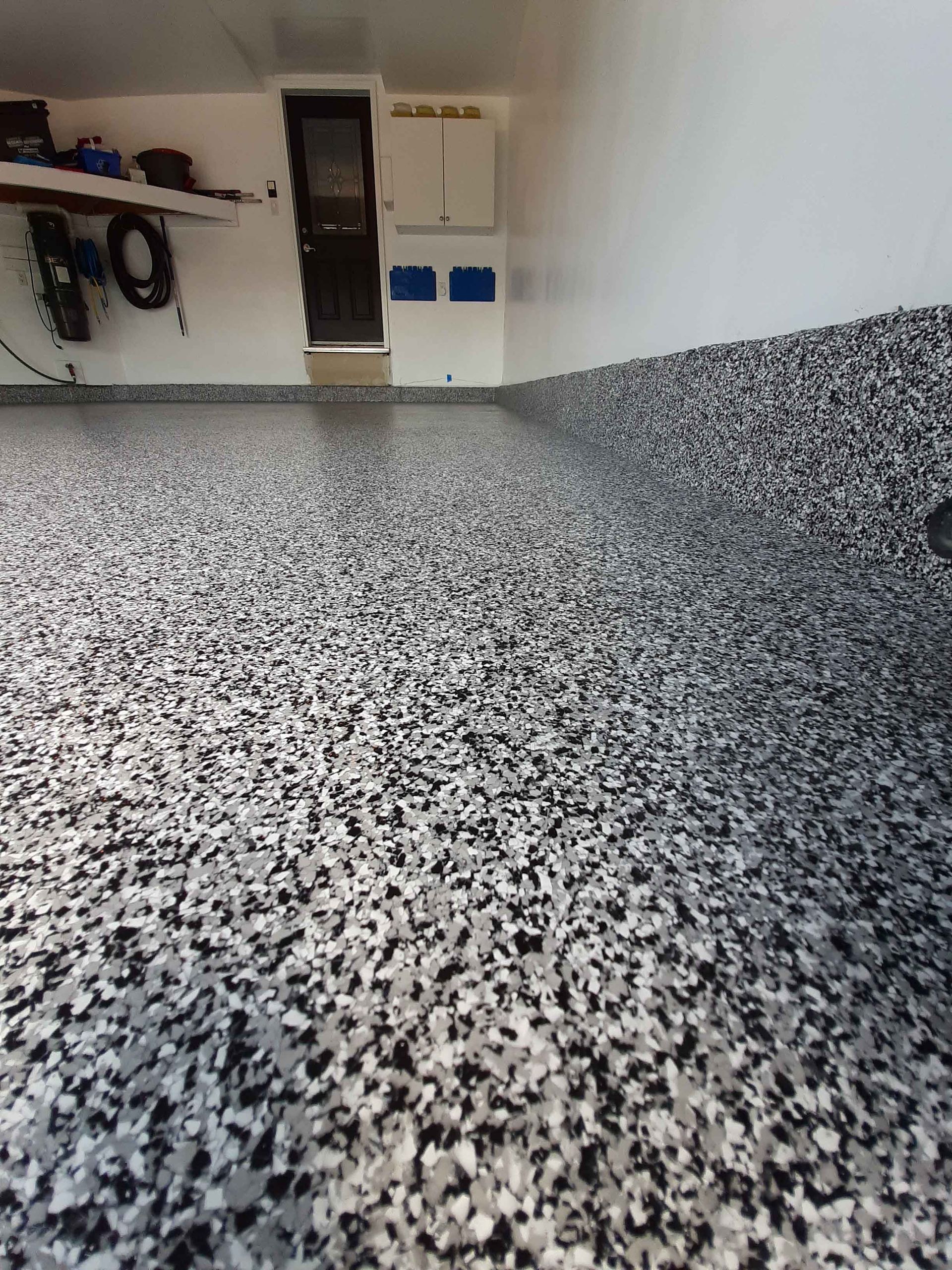 A garage with a black and white floor and a white wall.