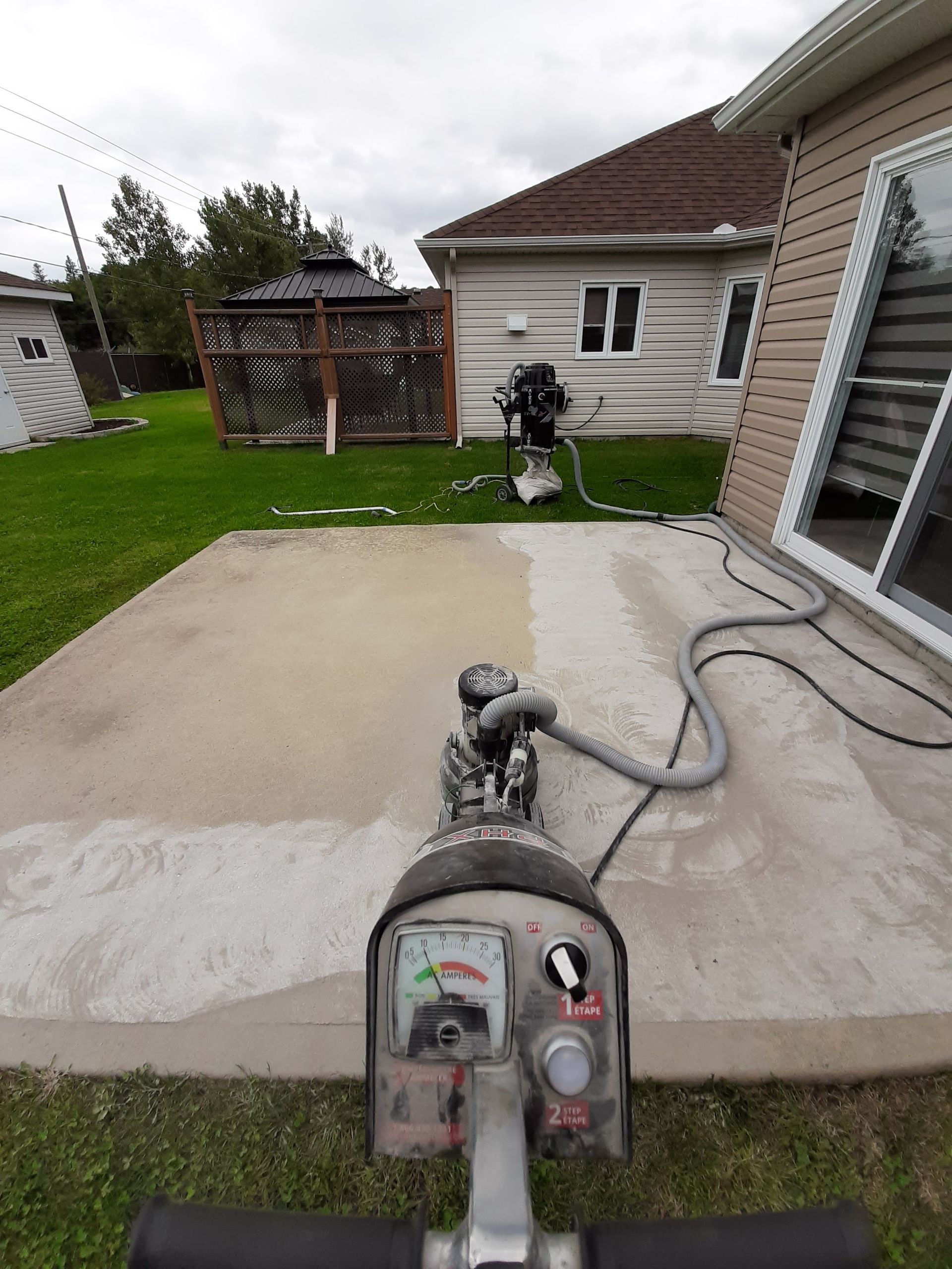 A machine is cleaning a concrete patio in front of a house.