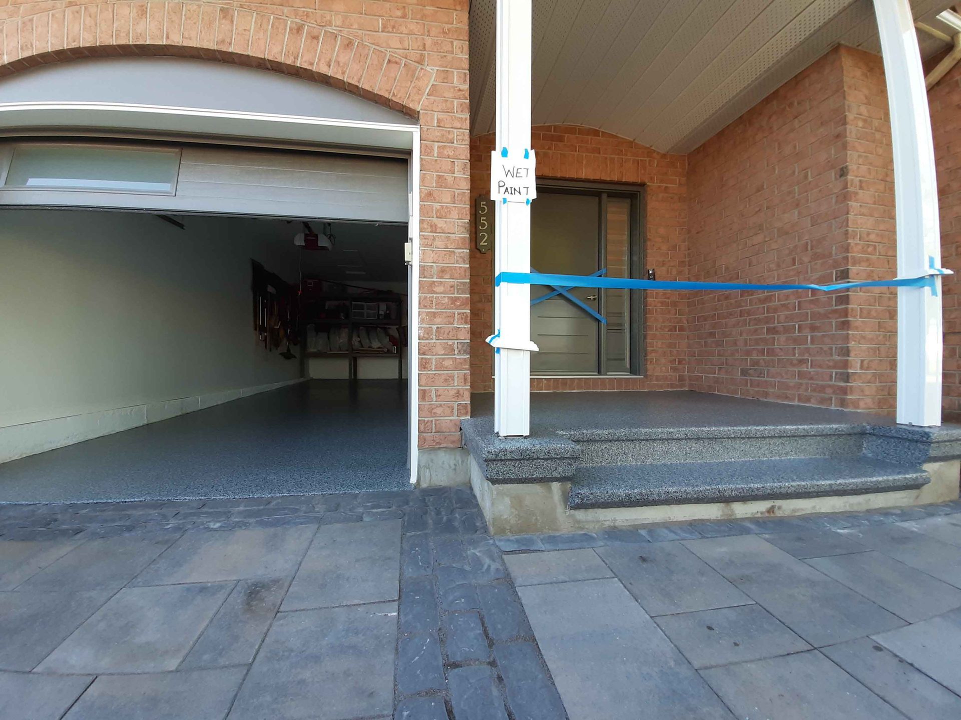 A brick house with a garage door open and stairs leading to it.