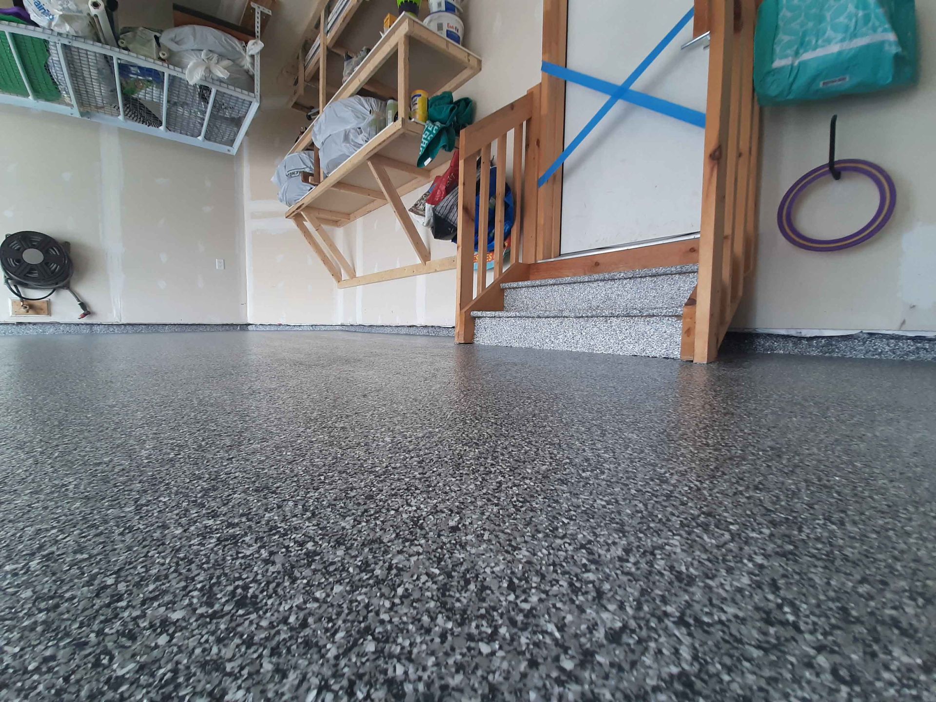 A garage with a gray floor and a wooden staircase.