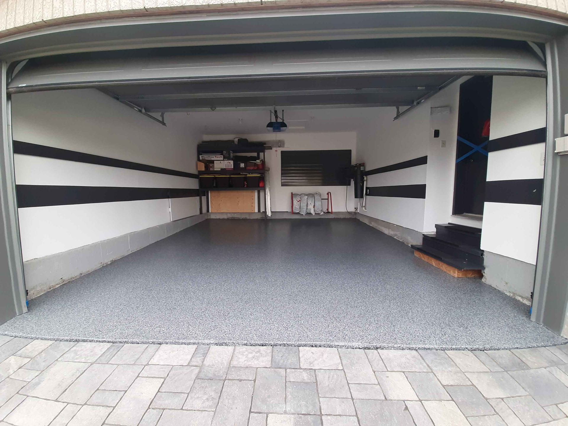 A garage with the door open and a brick floor