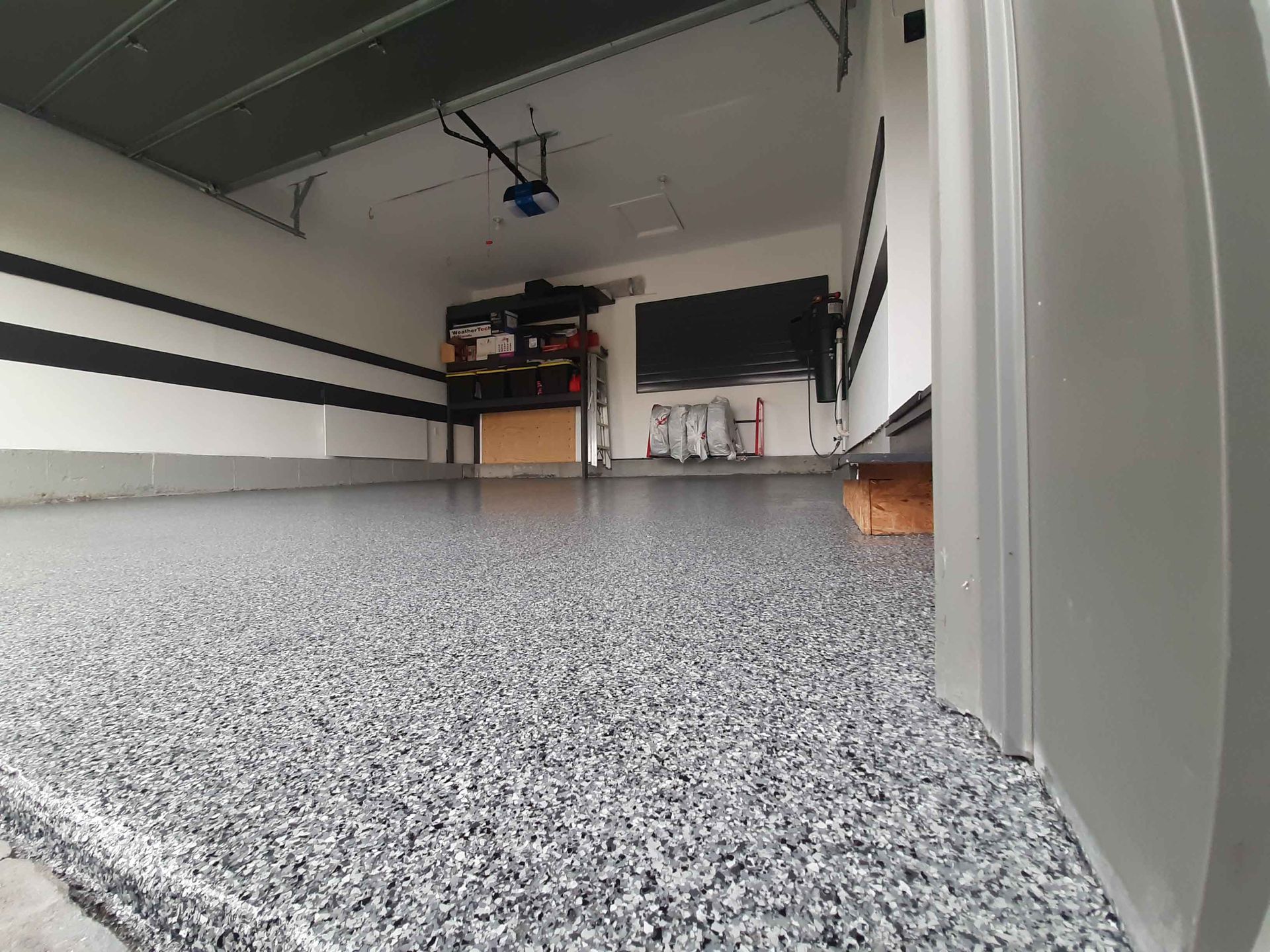 A garage with a gray floor and a black and white wall.