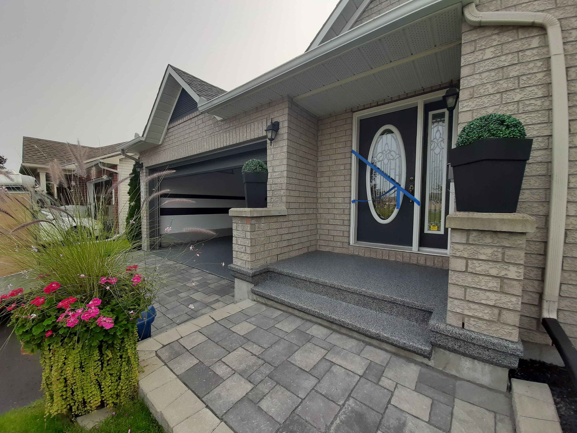 A brick house with a black door and a brick walkway leading to it.