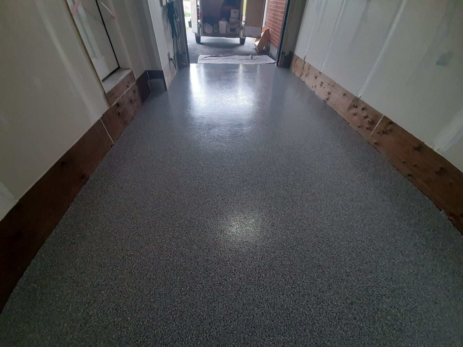 A hallway with a concrete floor and a wooden border.