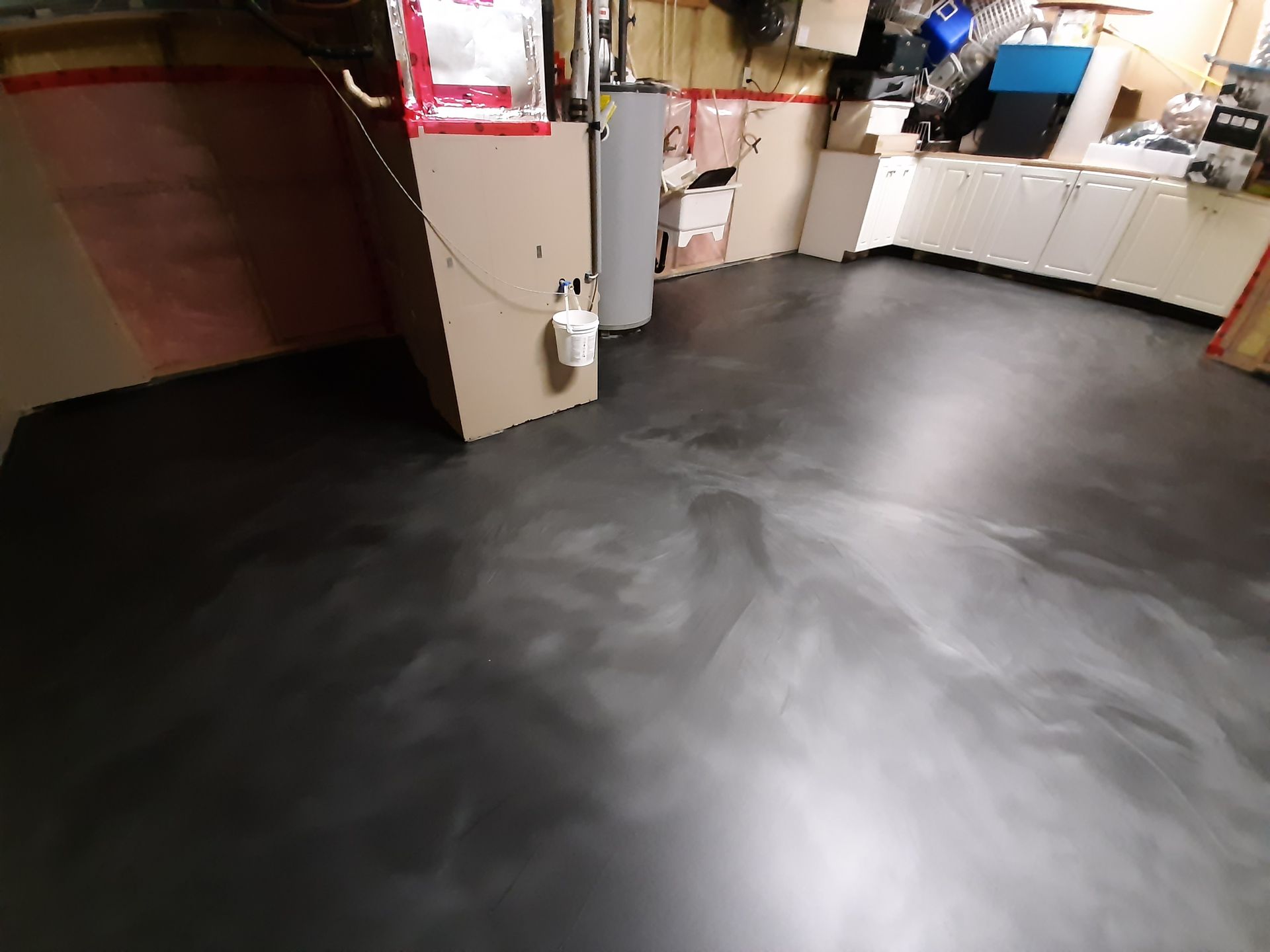 A room with a black floor and a bucket on the wall.