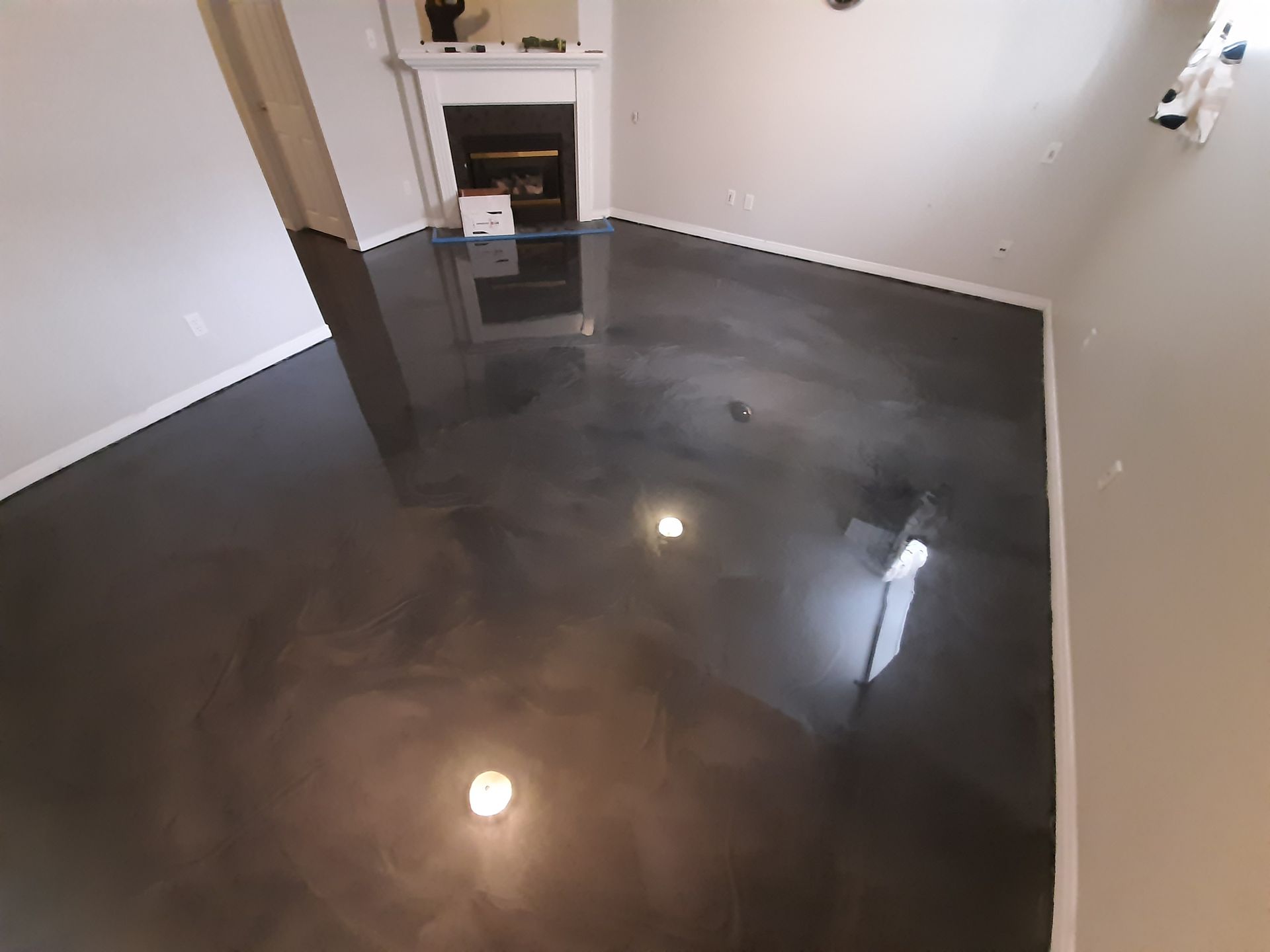 A living room with a black metallic floor and a fireplace.