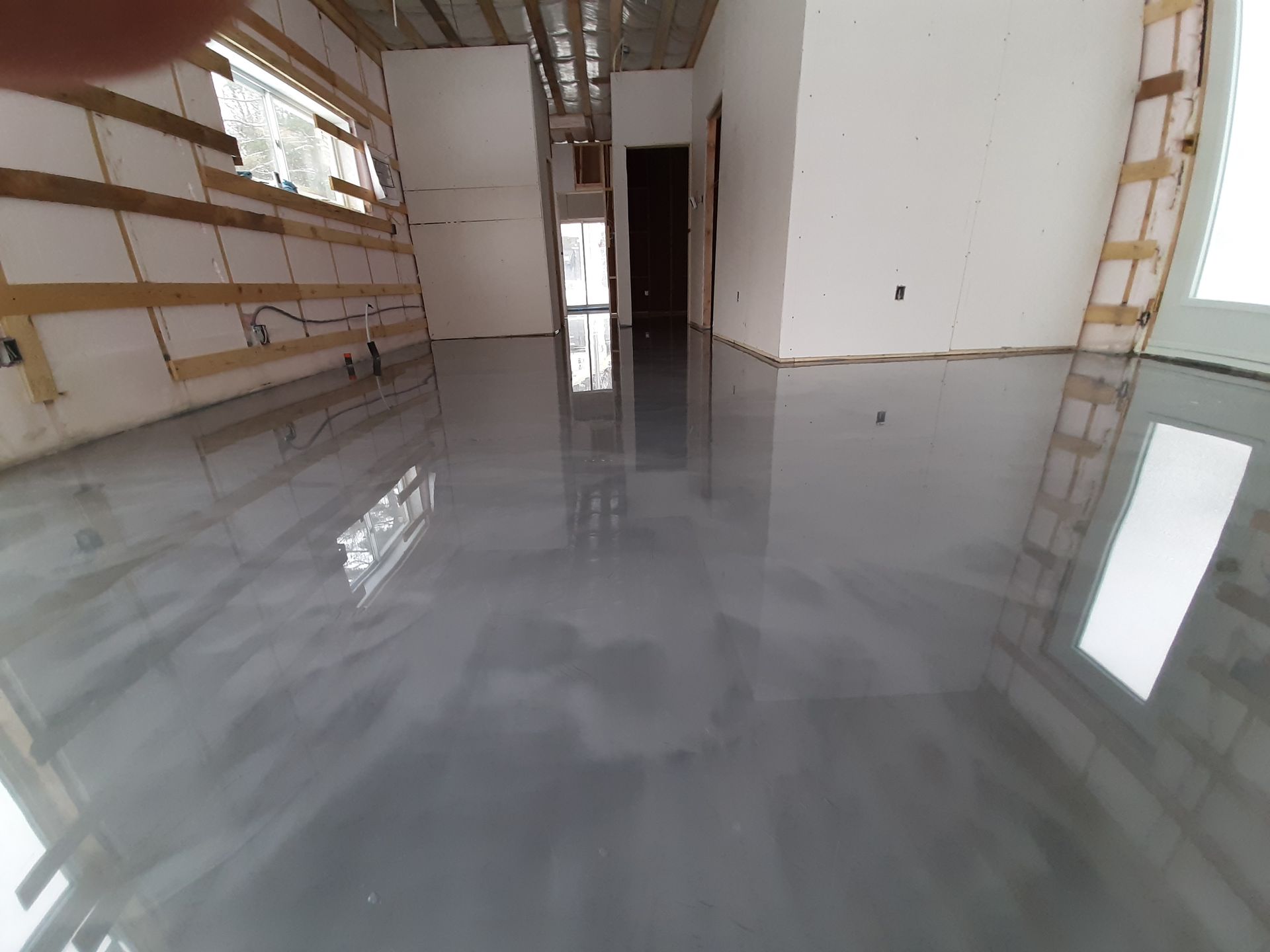 A room with a shiny gray floor and a ladder in the corner.