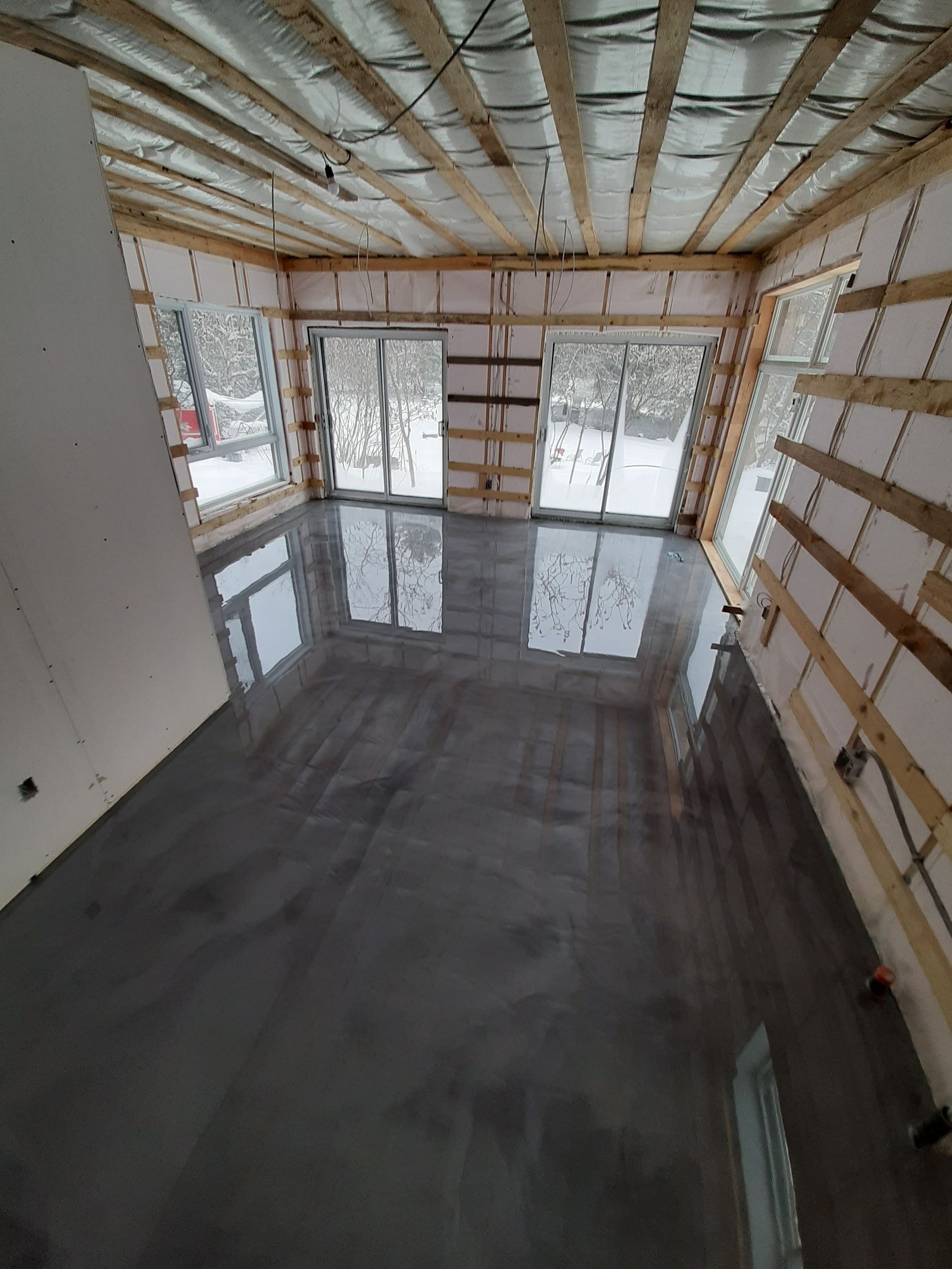 A large room with a concrete floor and sliding glass doors.