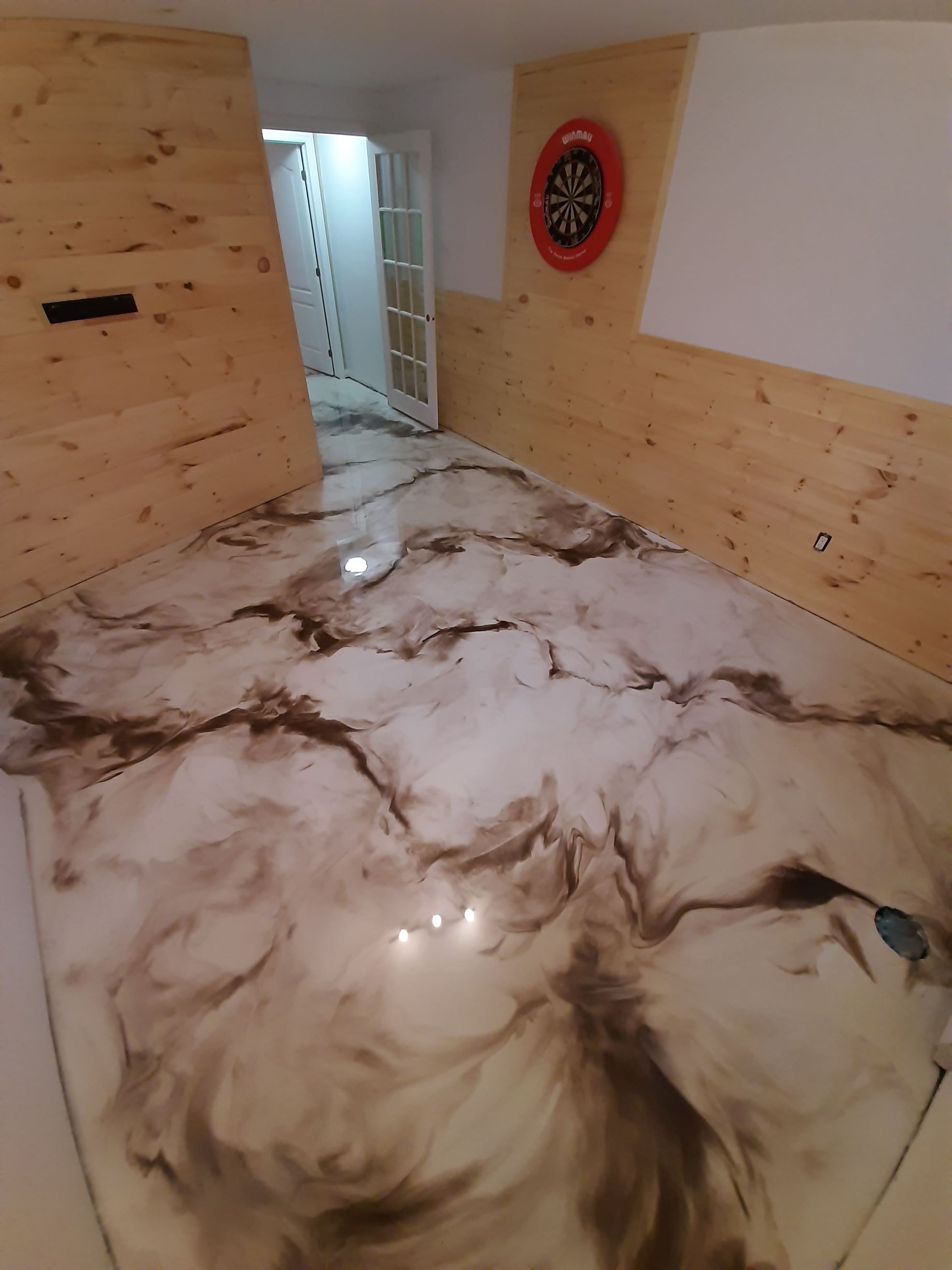A room with a dart board on the wall and a marble floor