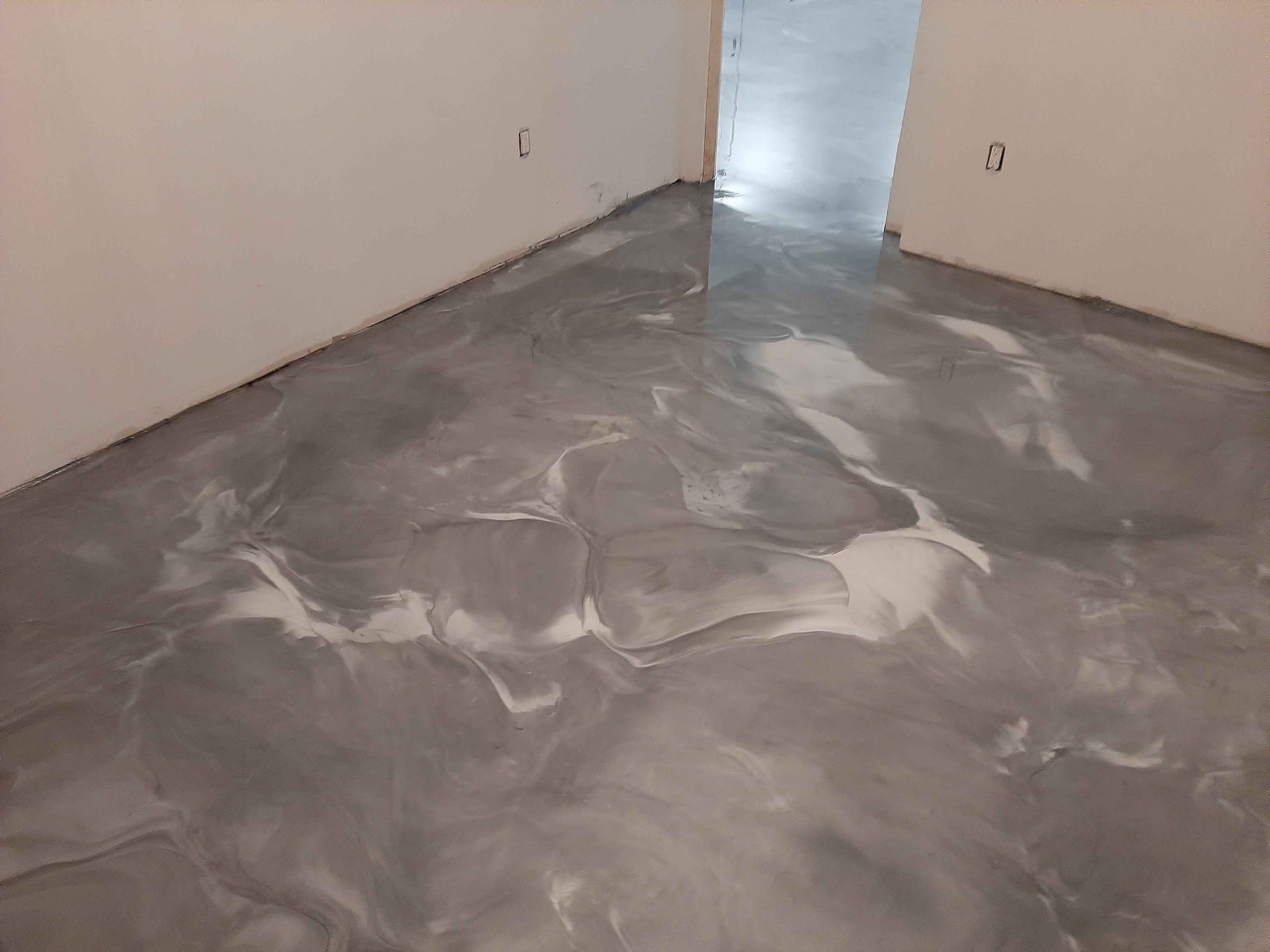 A room with a gray and white marble floor and white walls.