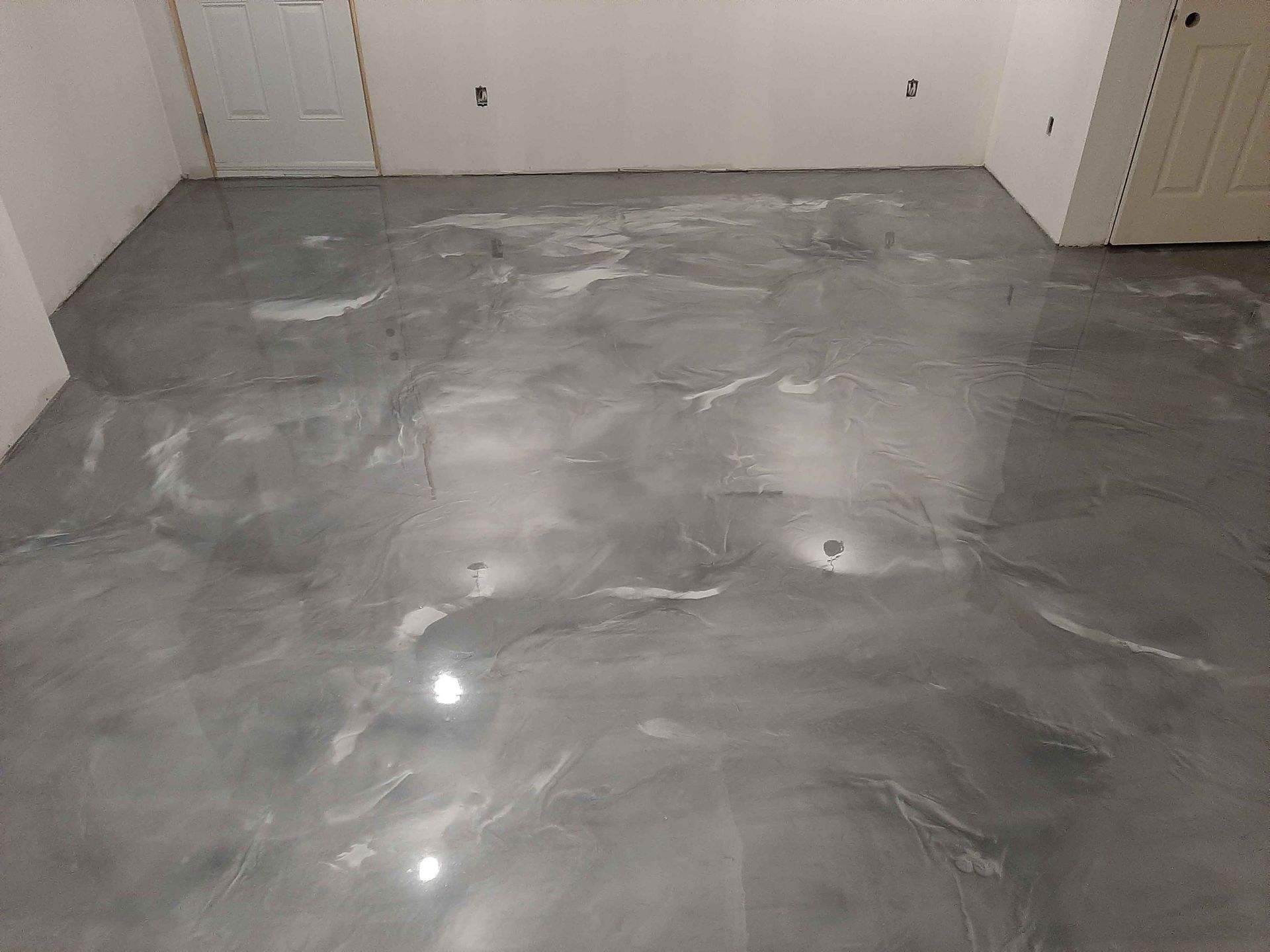 A room with a shiny metallic floor and a door.