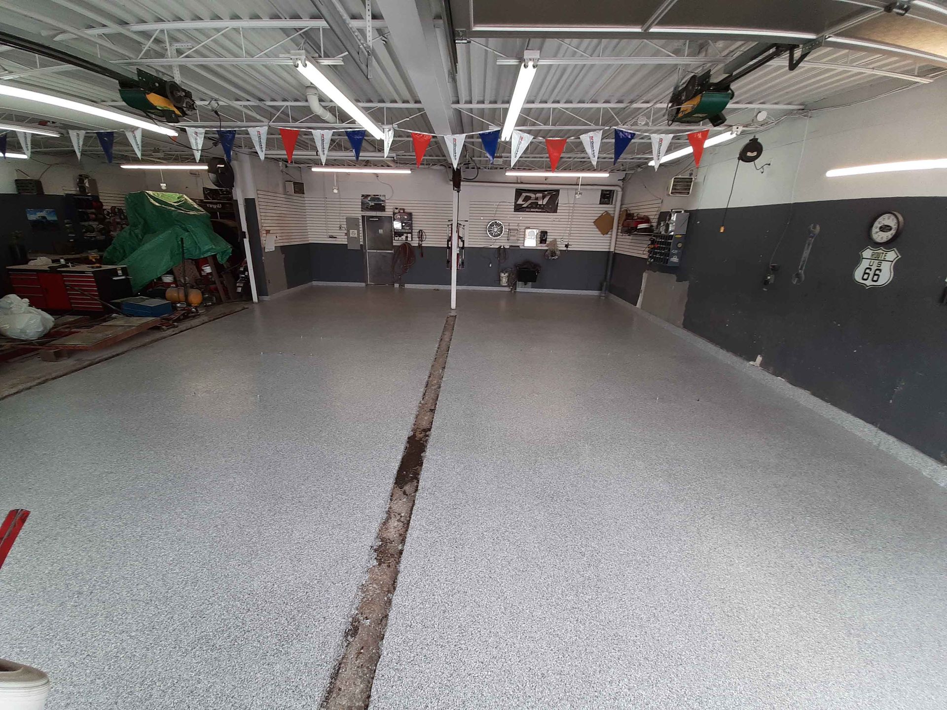 A garage with a concrete floor and flags hanging from the ceiling.