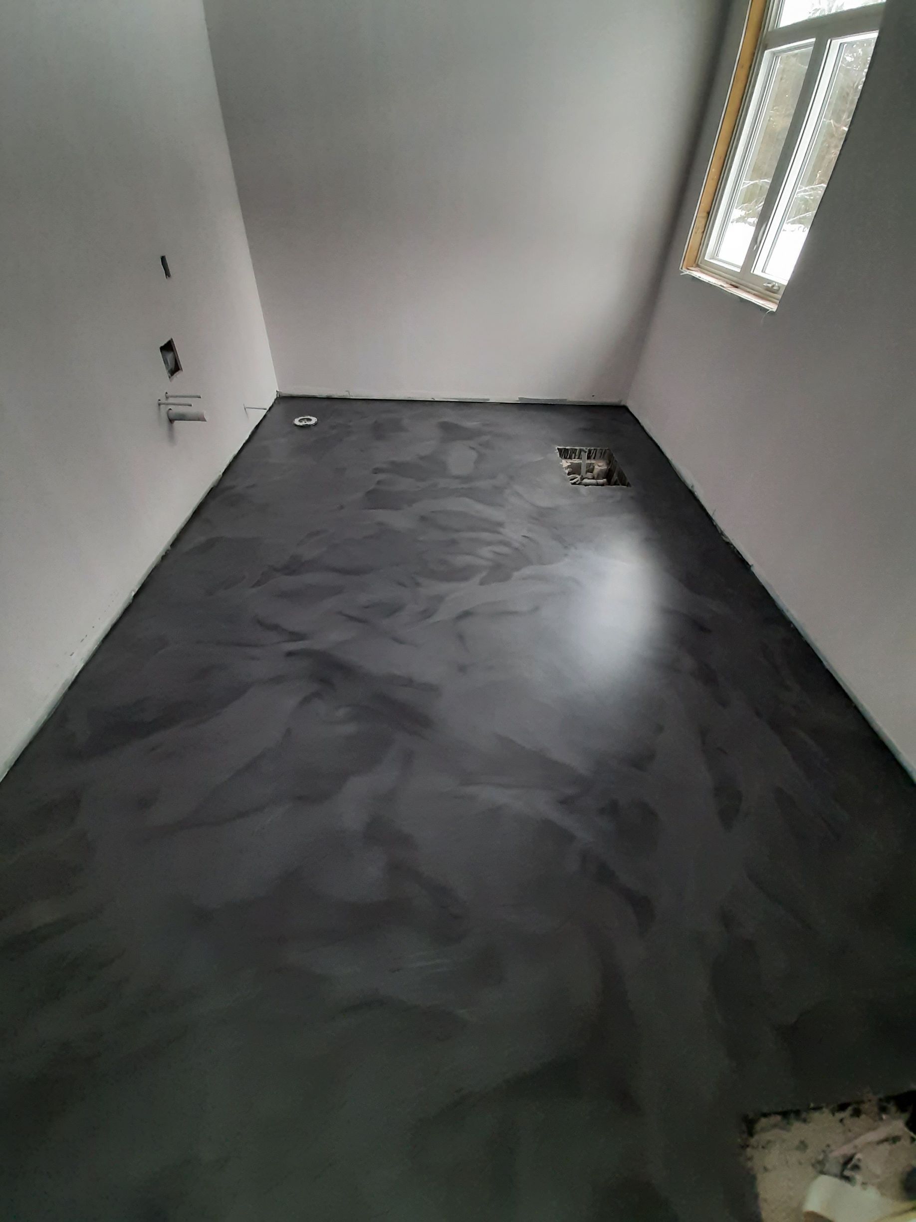 A room with a black floor and a window.