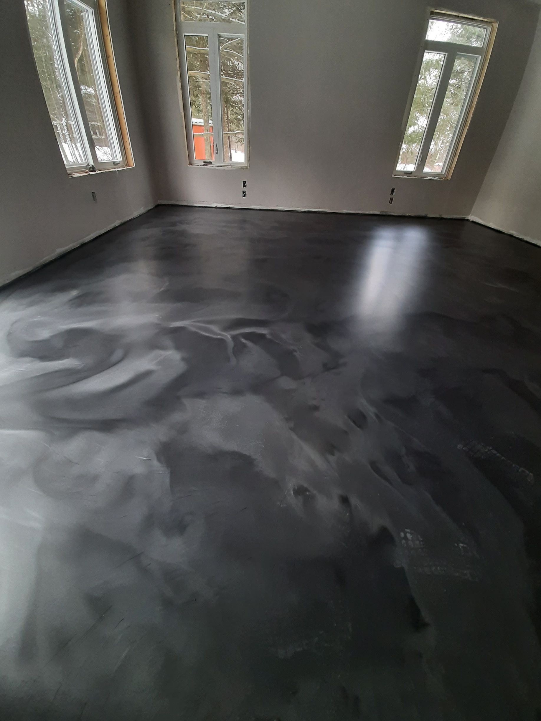 A room with a black floor and a lot of windows.