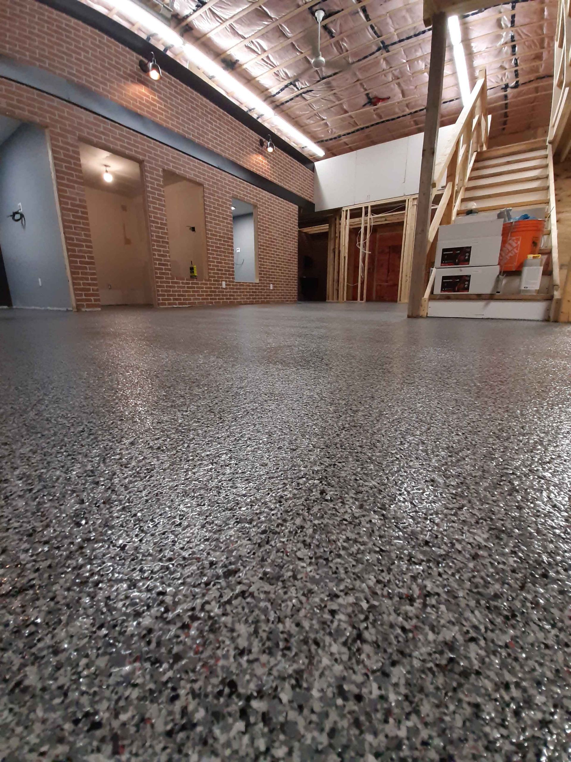 A large room with a staircase and a gray floor.