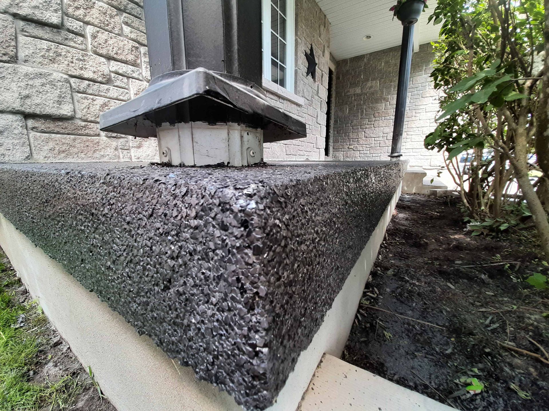 A close up of a concrete porch with a brick wall in the background.