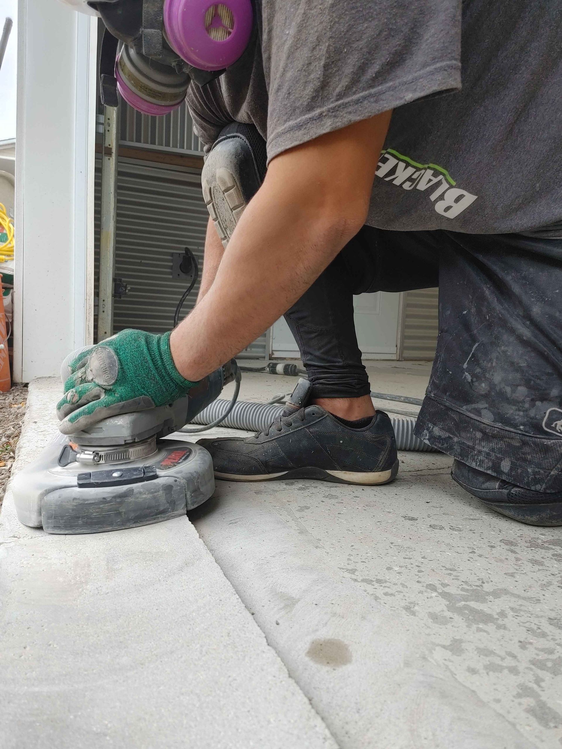 A man is grinding a concrete surface with a grinder.