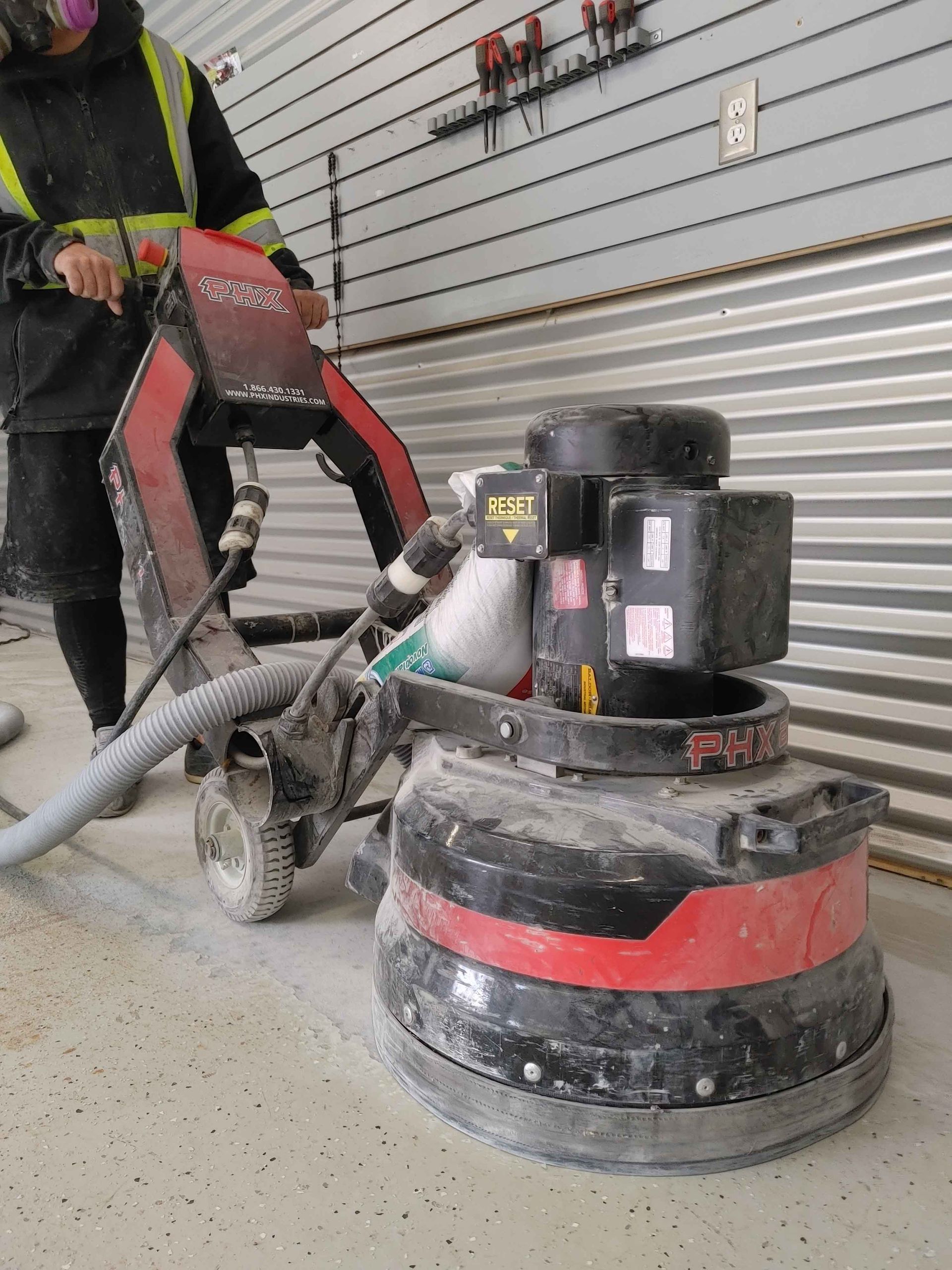 A man is using a grinder on a concrete floor.