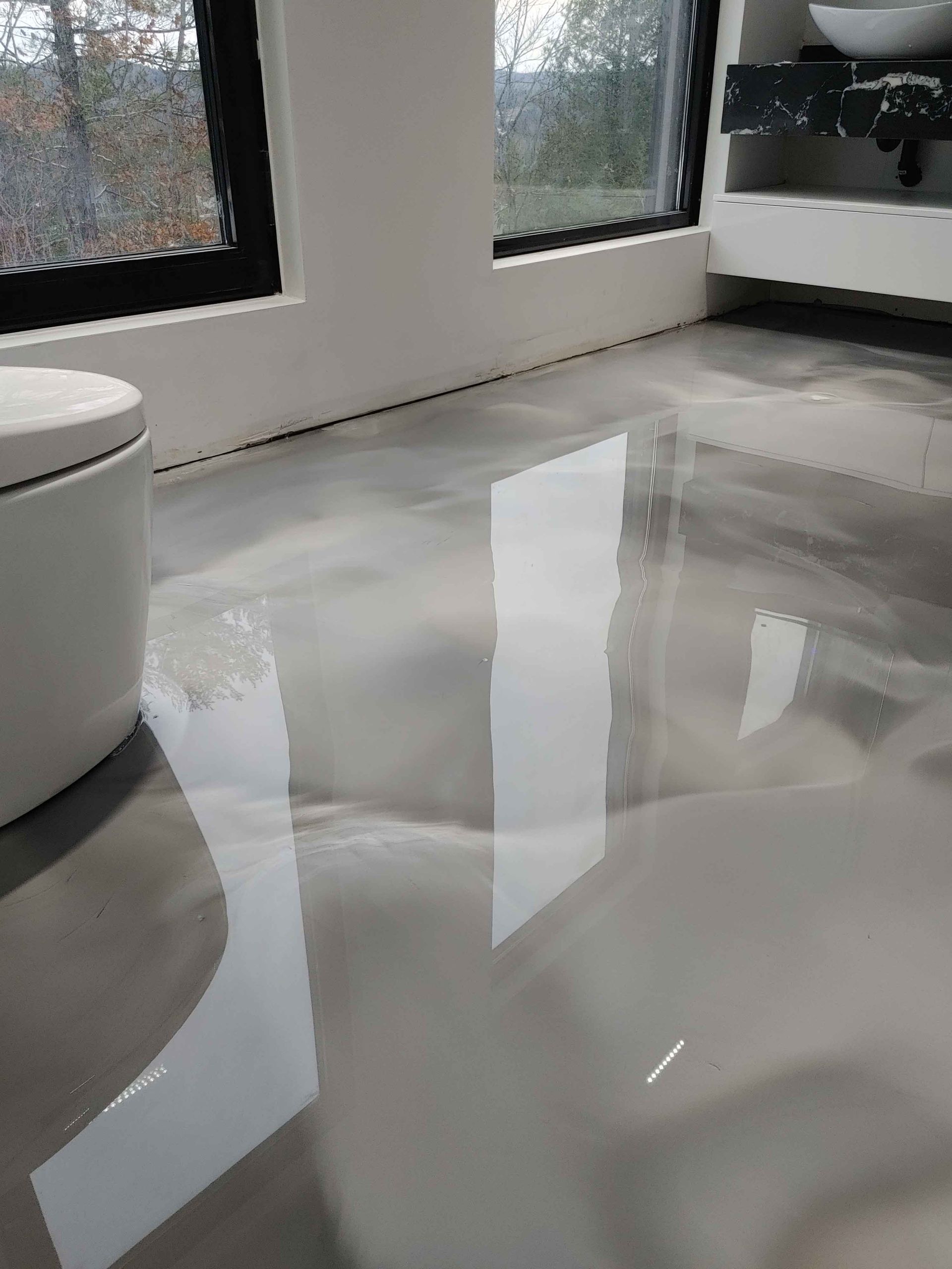 A bathroom with a shiny floor and a toilet.