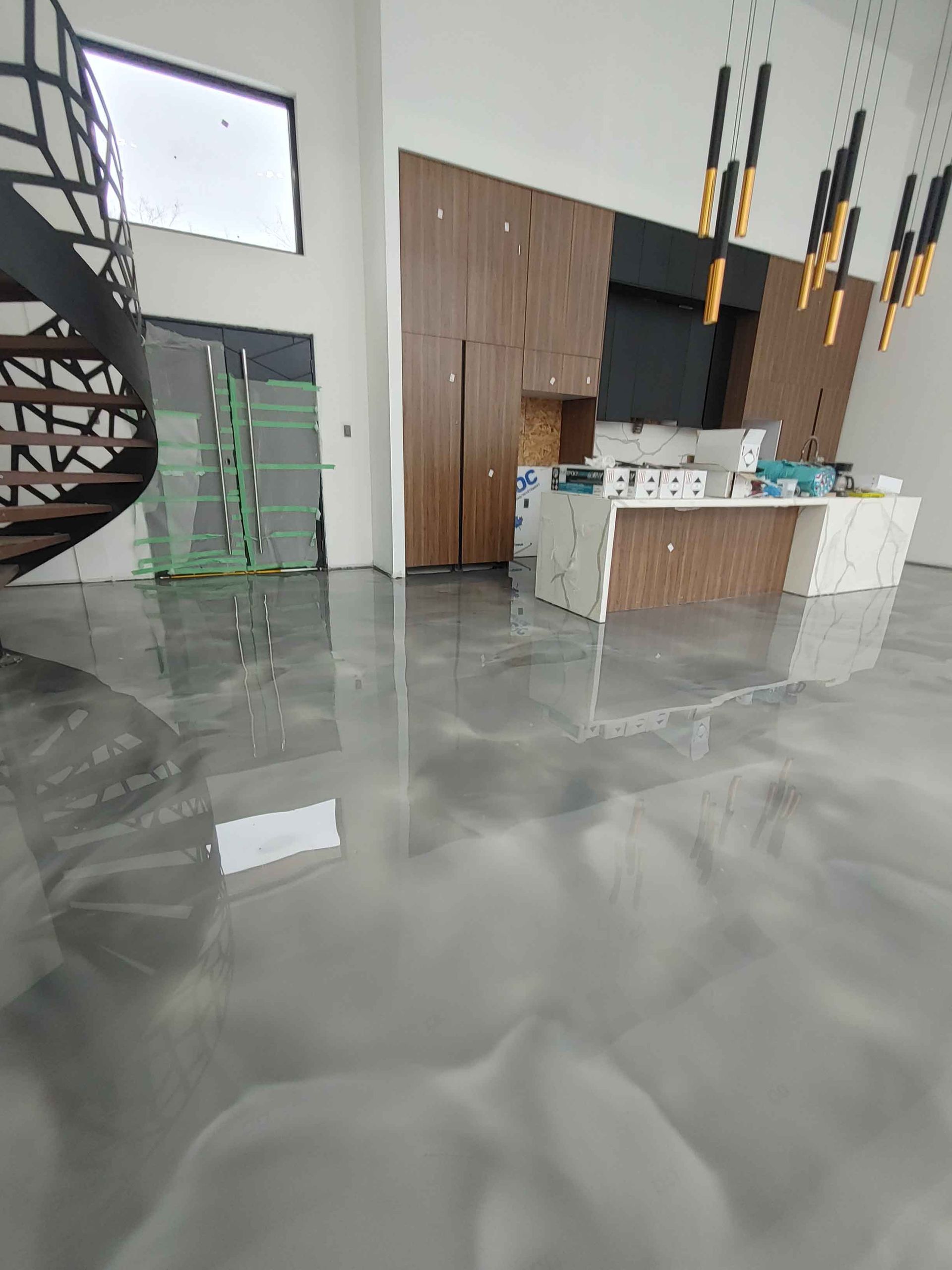 A kitchen with a spiral staircase and a shiny metallic floor.