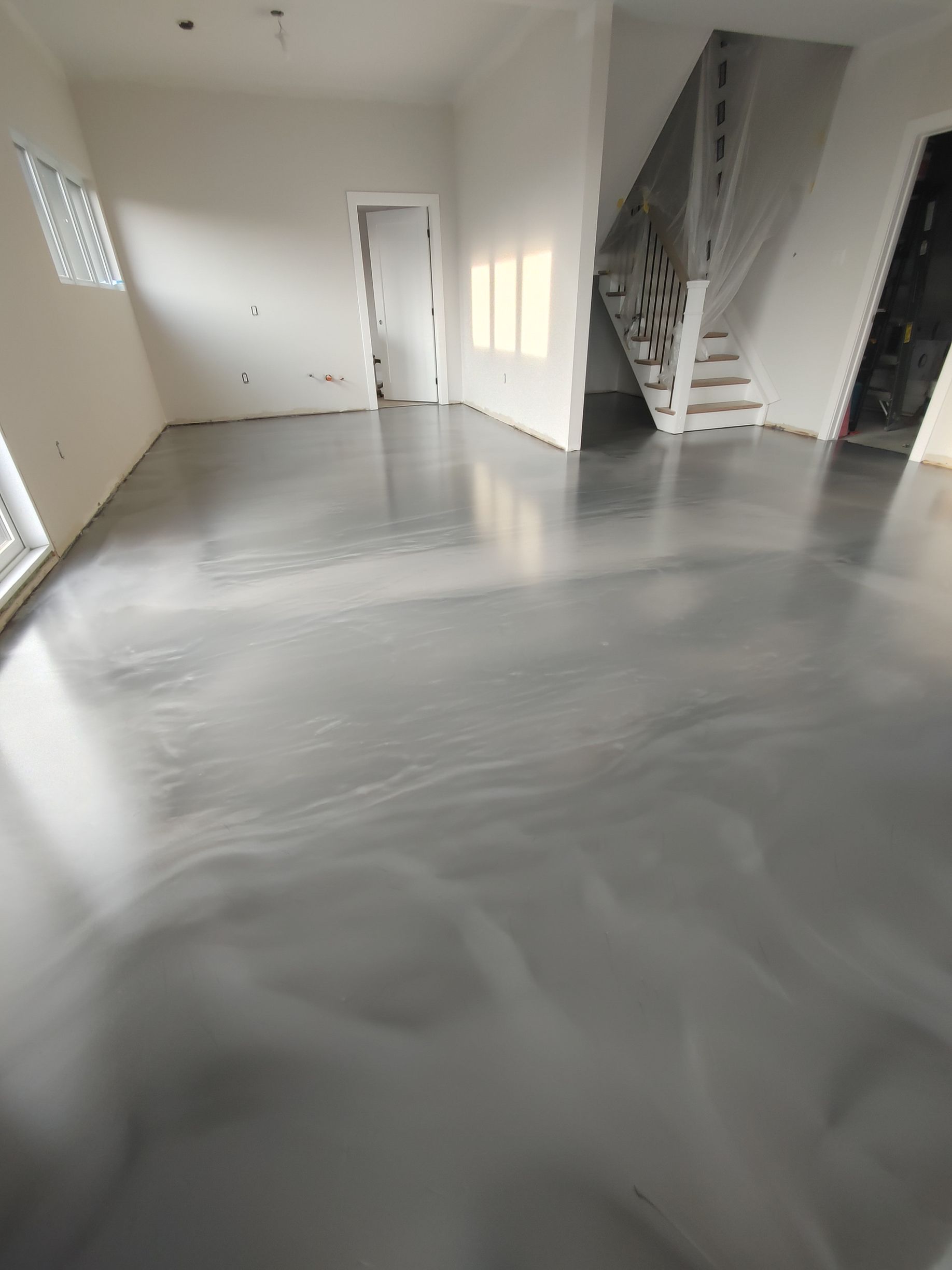 A living room with a shiny metallic floor and stairs.