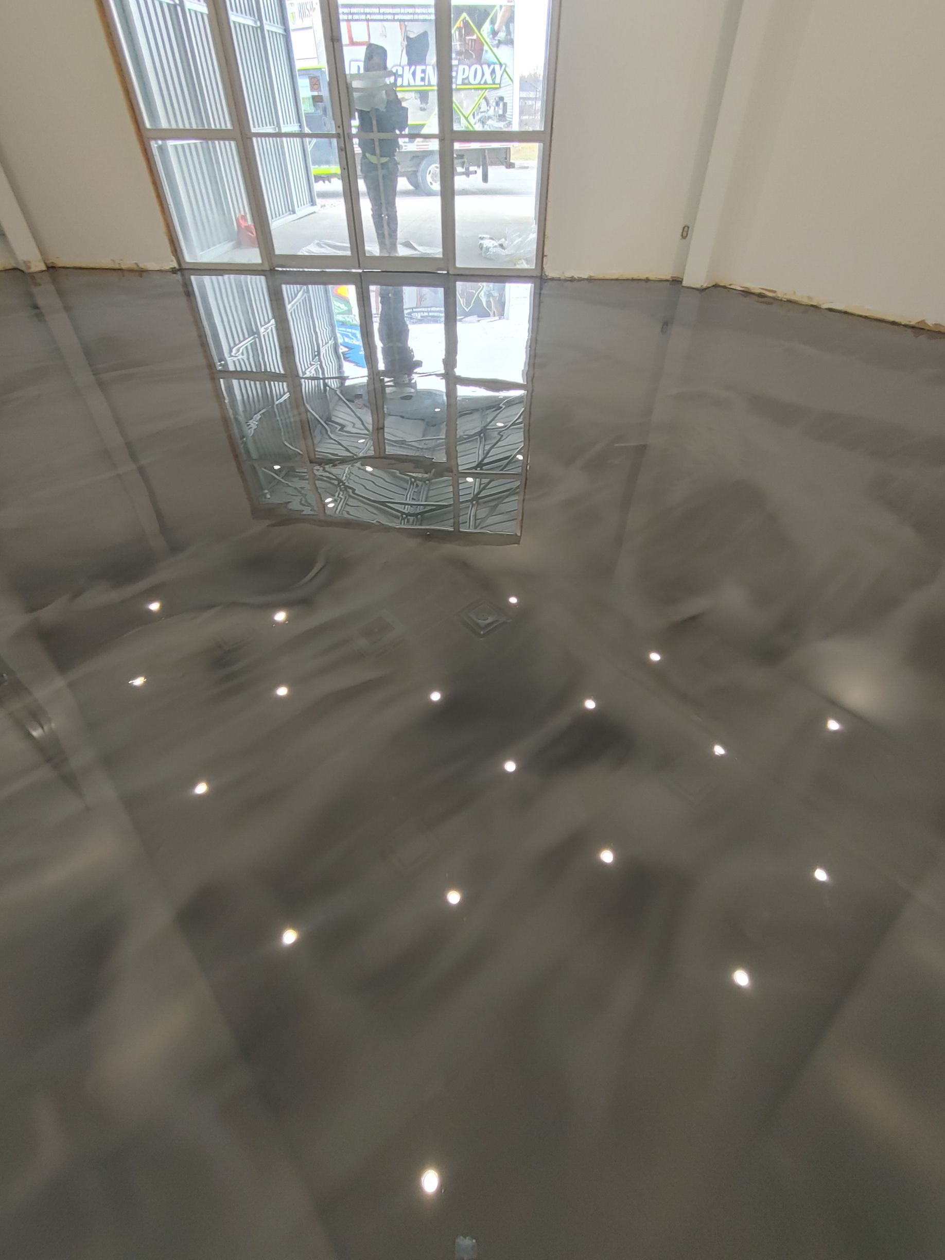 A person is standing in a room with a shiny floor and a window.