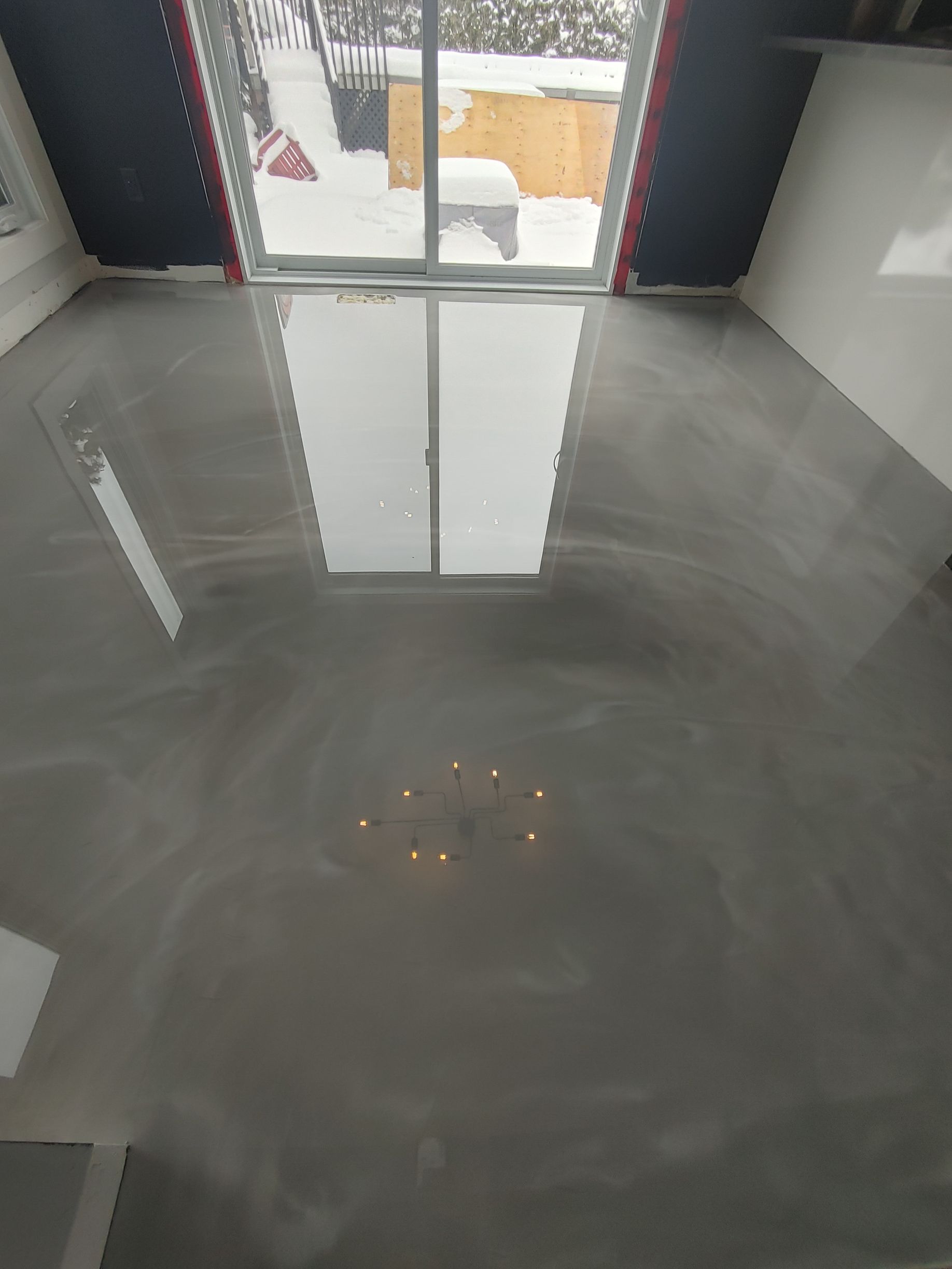 A room with a shiny concrete floor and a window.