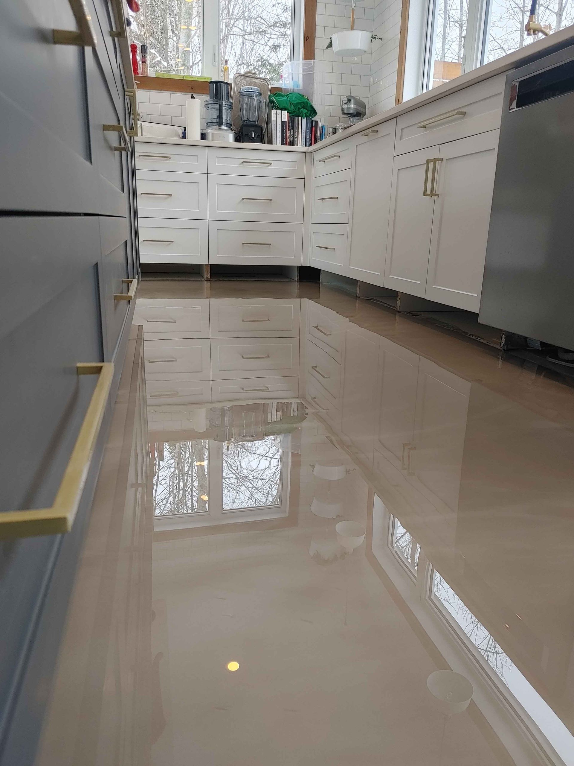 A kitchen with white cabinets and a shiny floor.