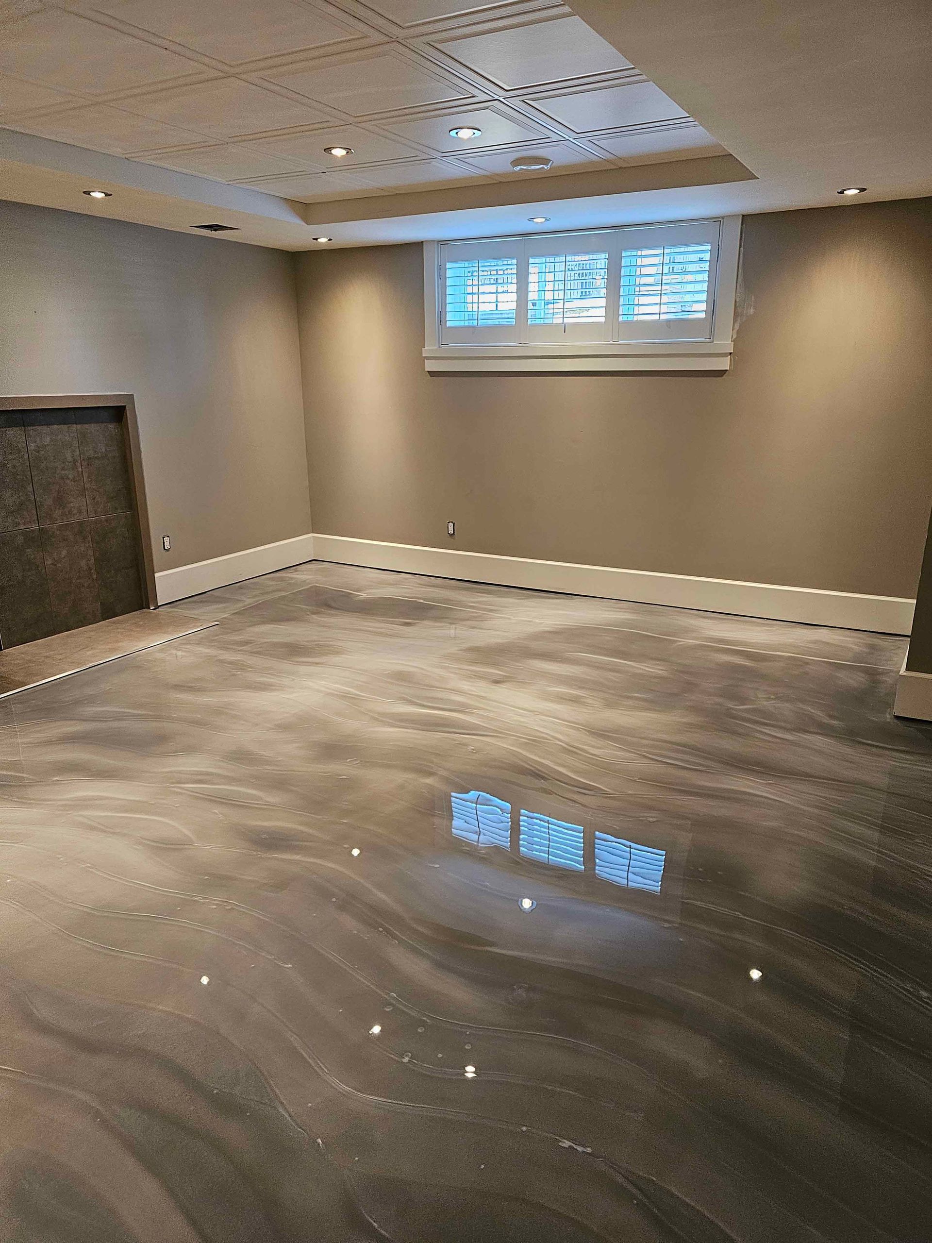 A basement with a shiny metallic floor and a window.