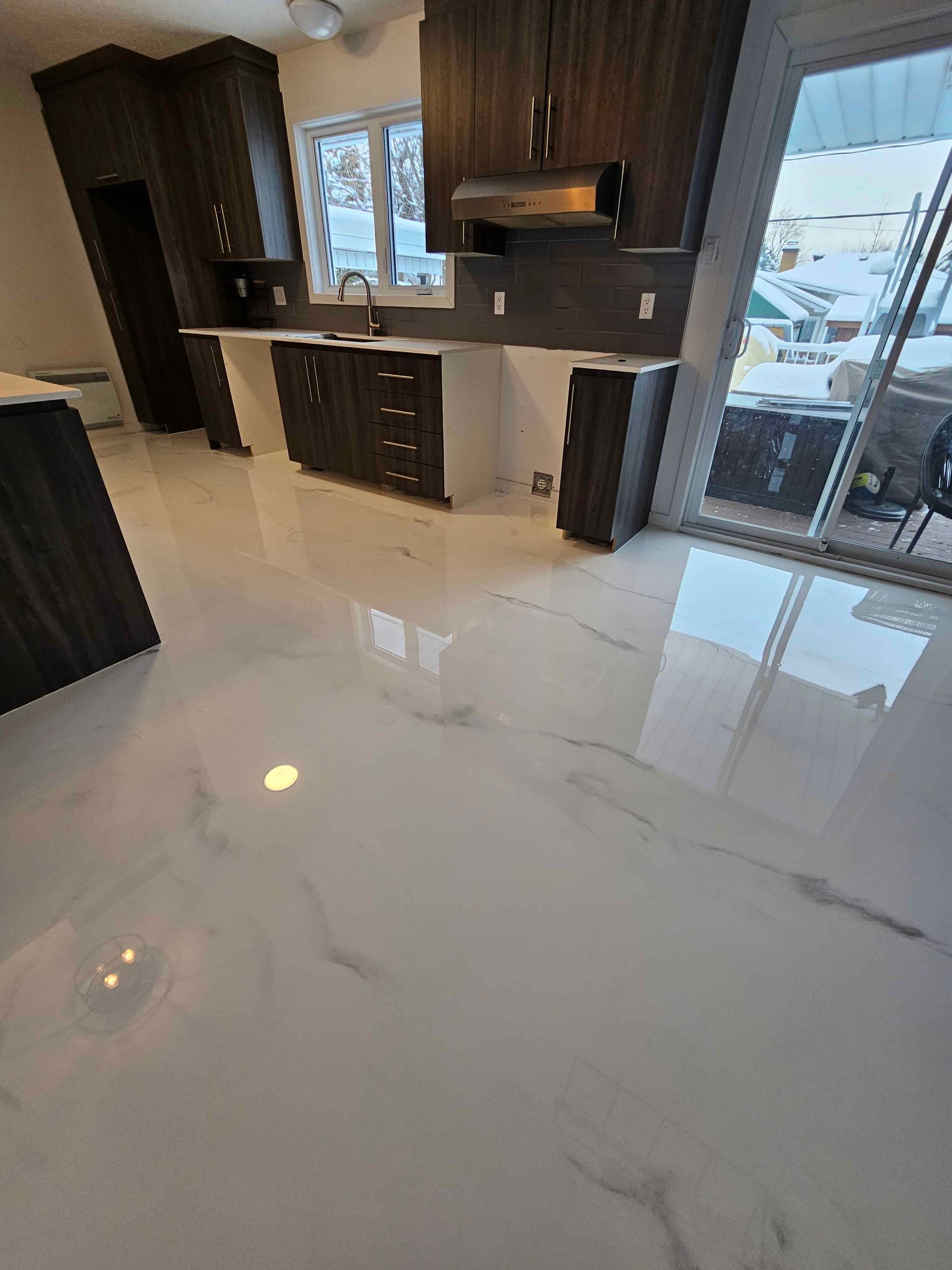 A kitchen with a marble floor and wooden cabinets.