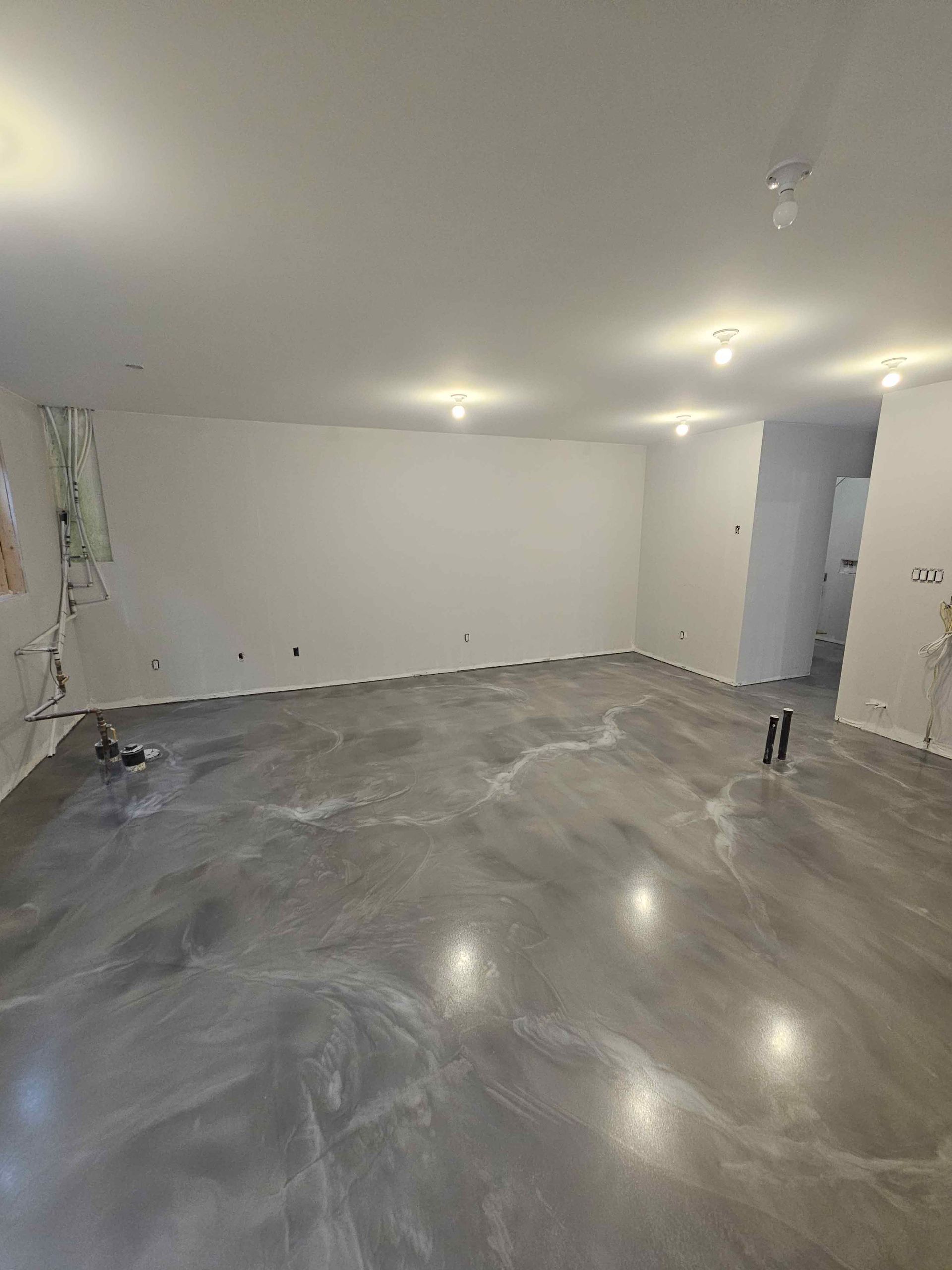 A large empty room with a concrete floor and white walls.
