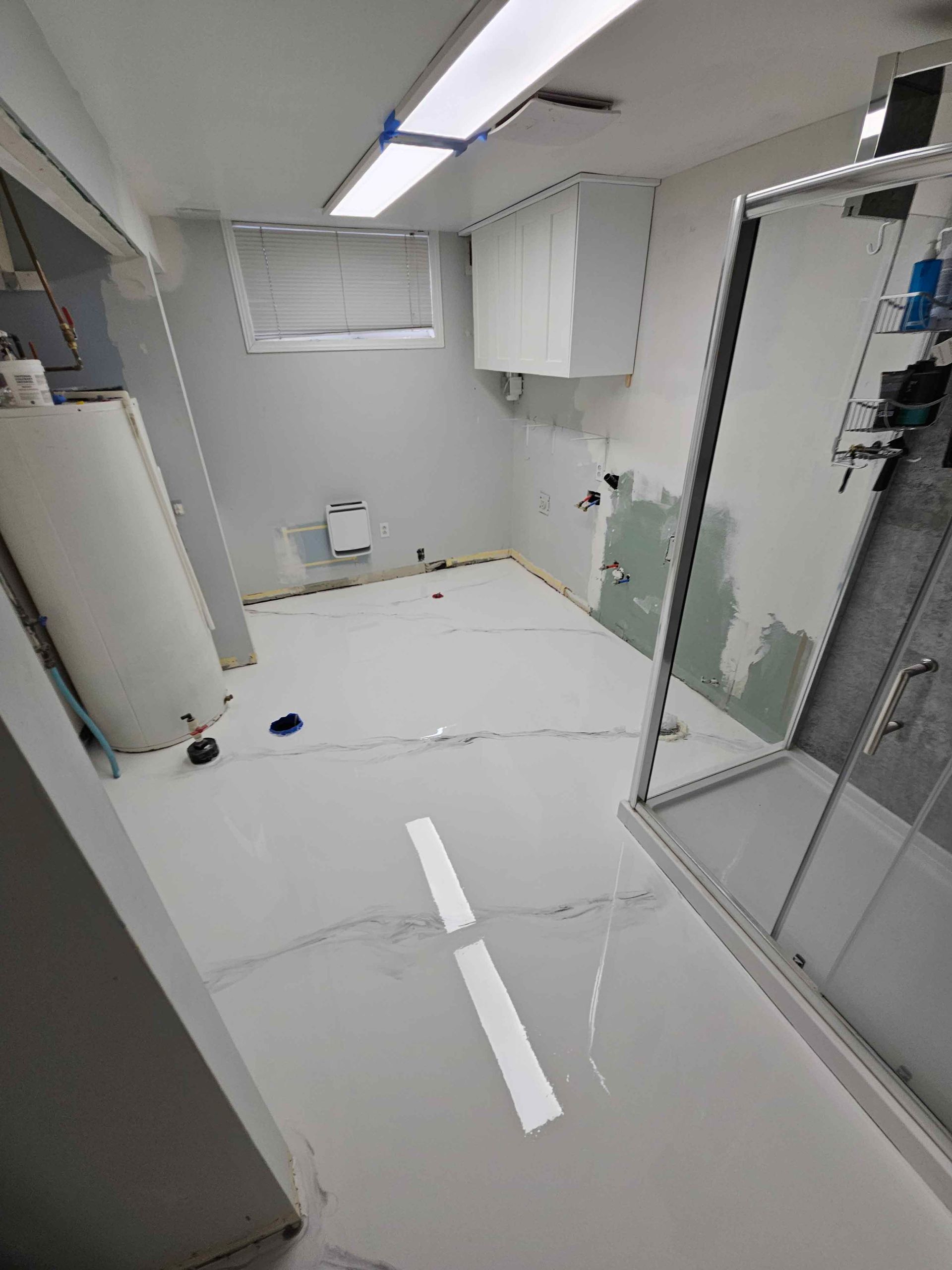 A bathroom with white tile floors and a shower stall.