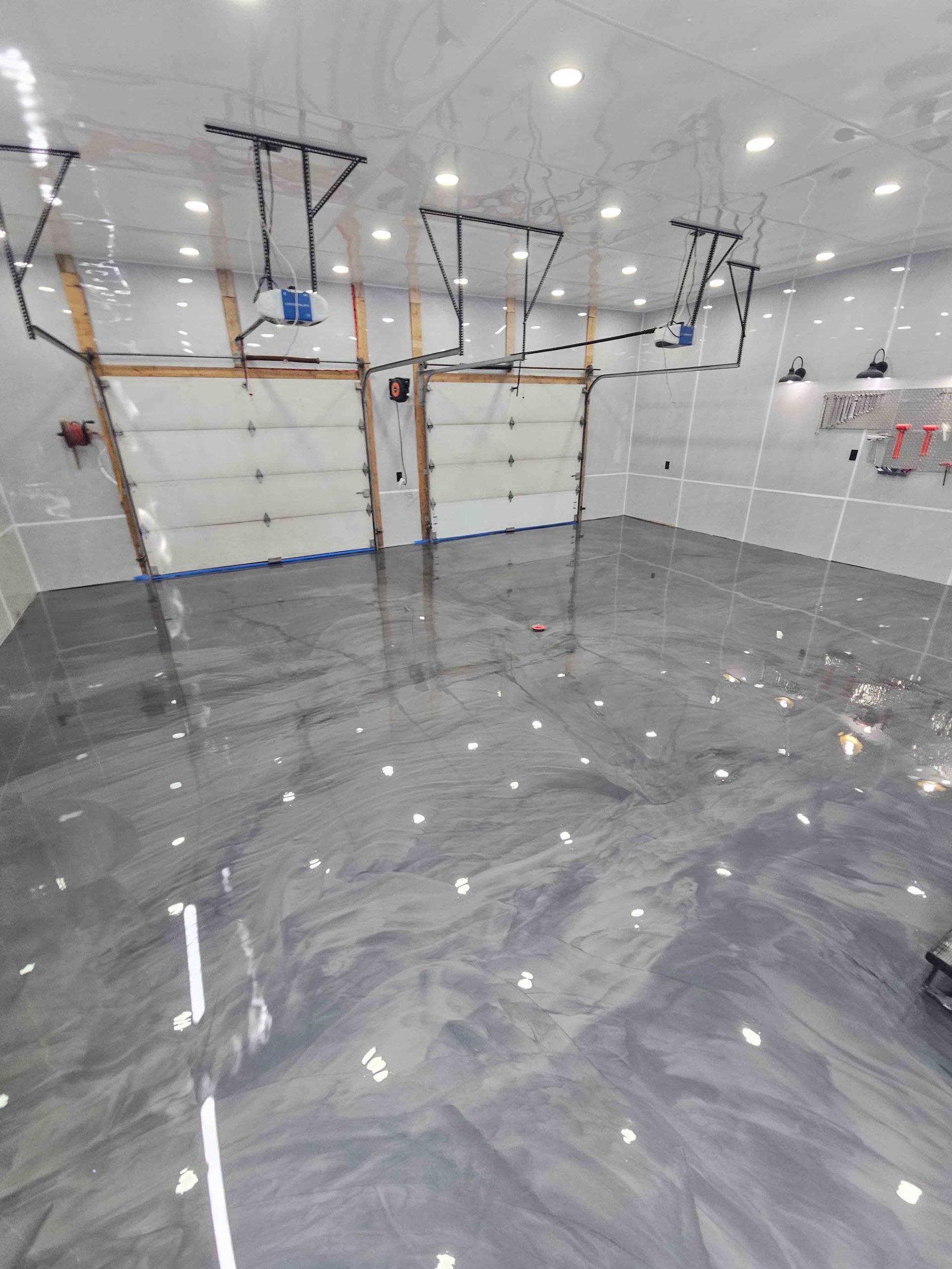 A garage with a shiny metallic floor and two garage doors.