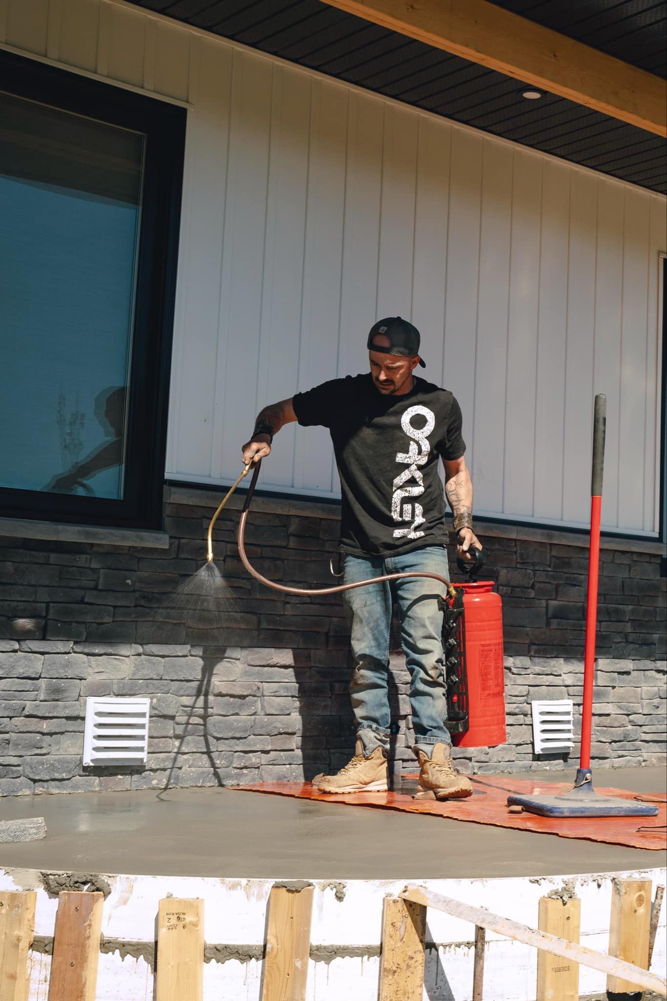 A man is standing in front of a building spraying concrete.